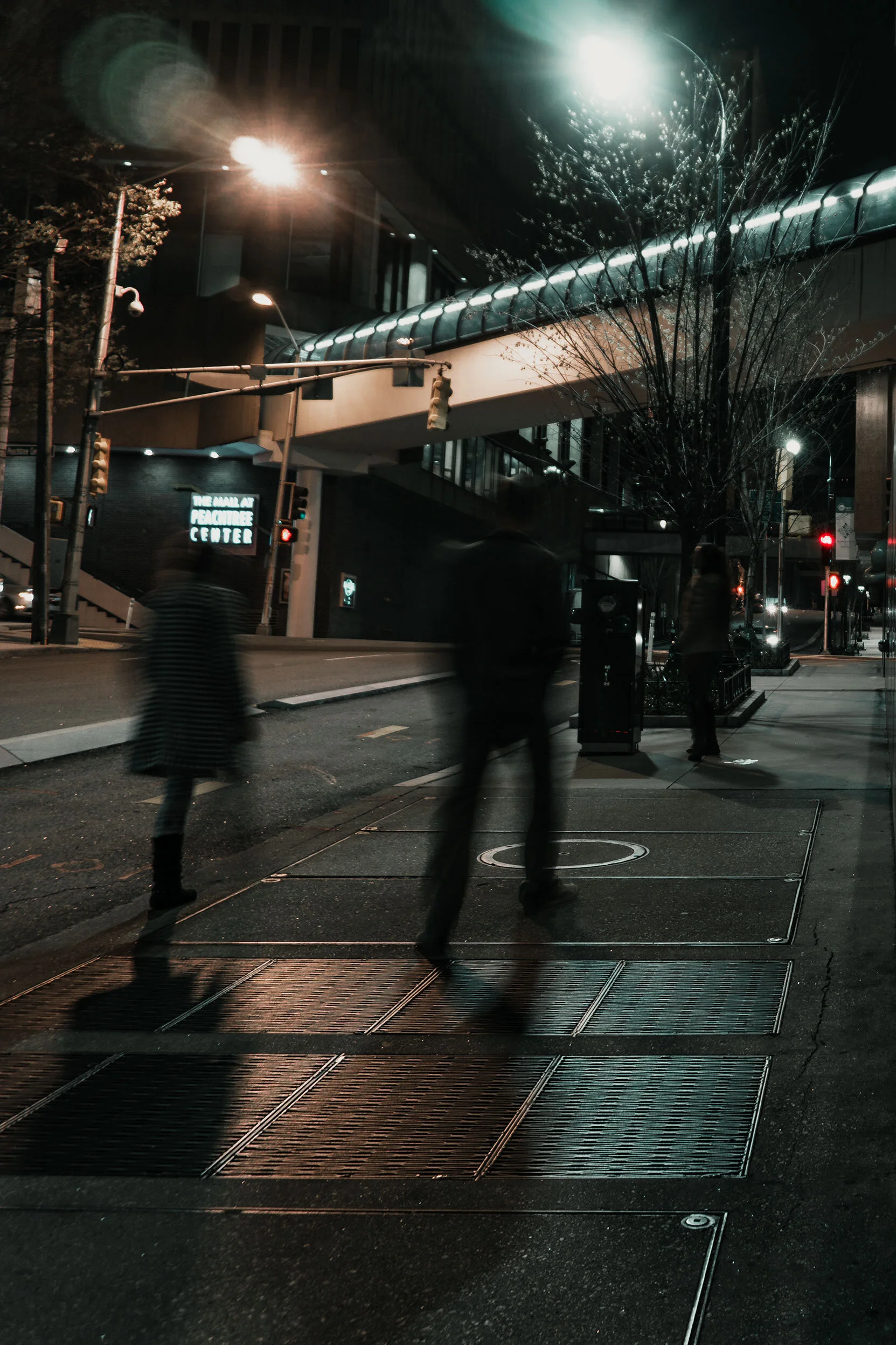 Blurred people walking down a street in Atlanta, Georgia. The scene is reflected in the black granite wall occupying the opposite half.