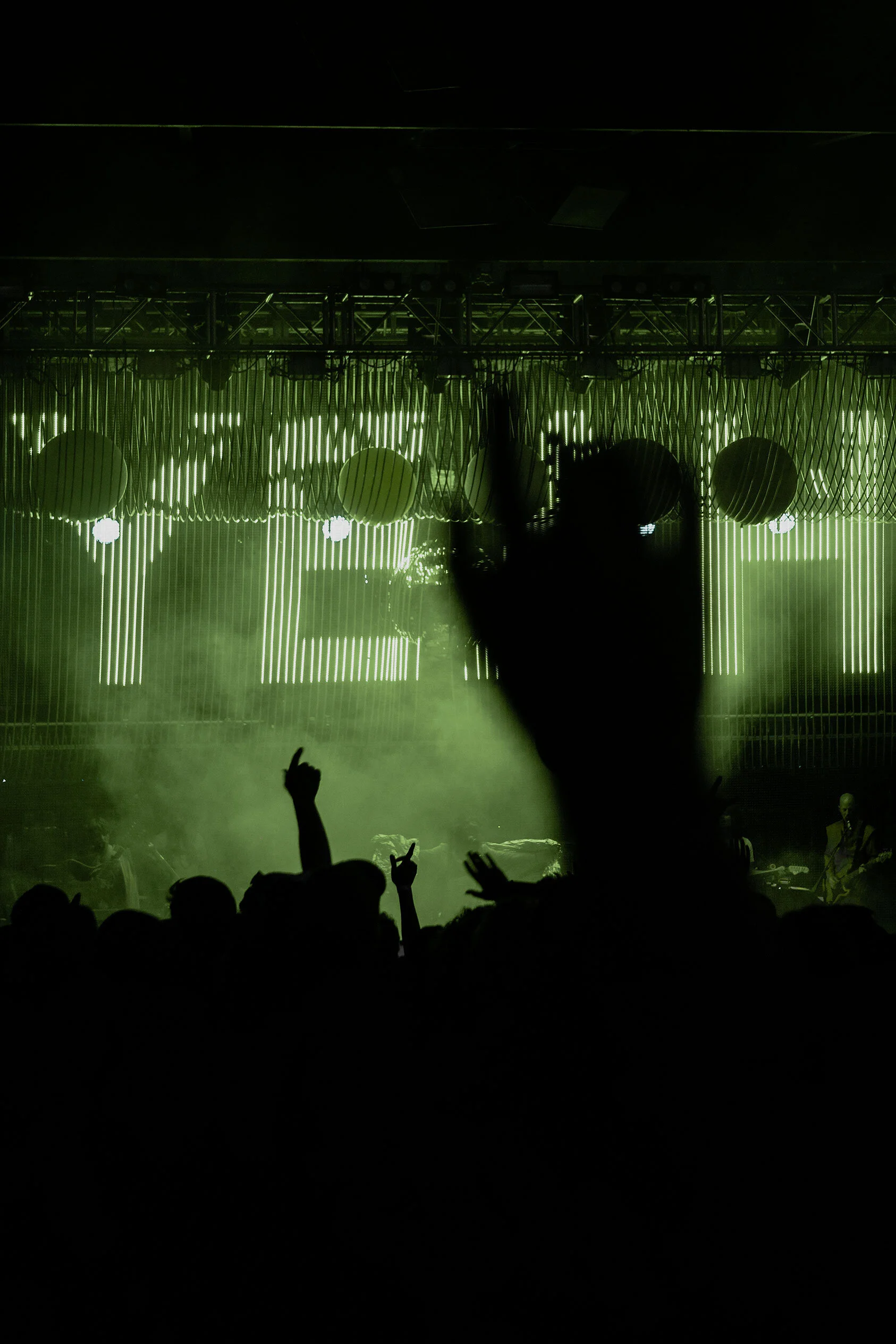 Outdoor concert stage at night, the word 'yeah' formed by green strings of LED lights illuminates stage and fog and silhouettes the crowd. The Flaming Lips in Ogden, Utah.