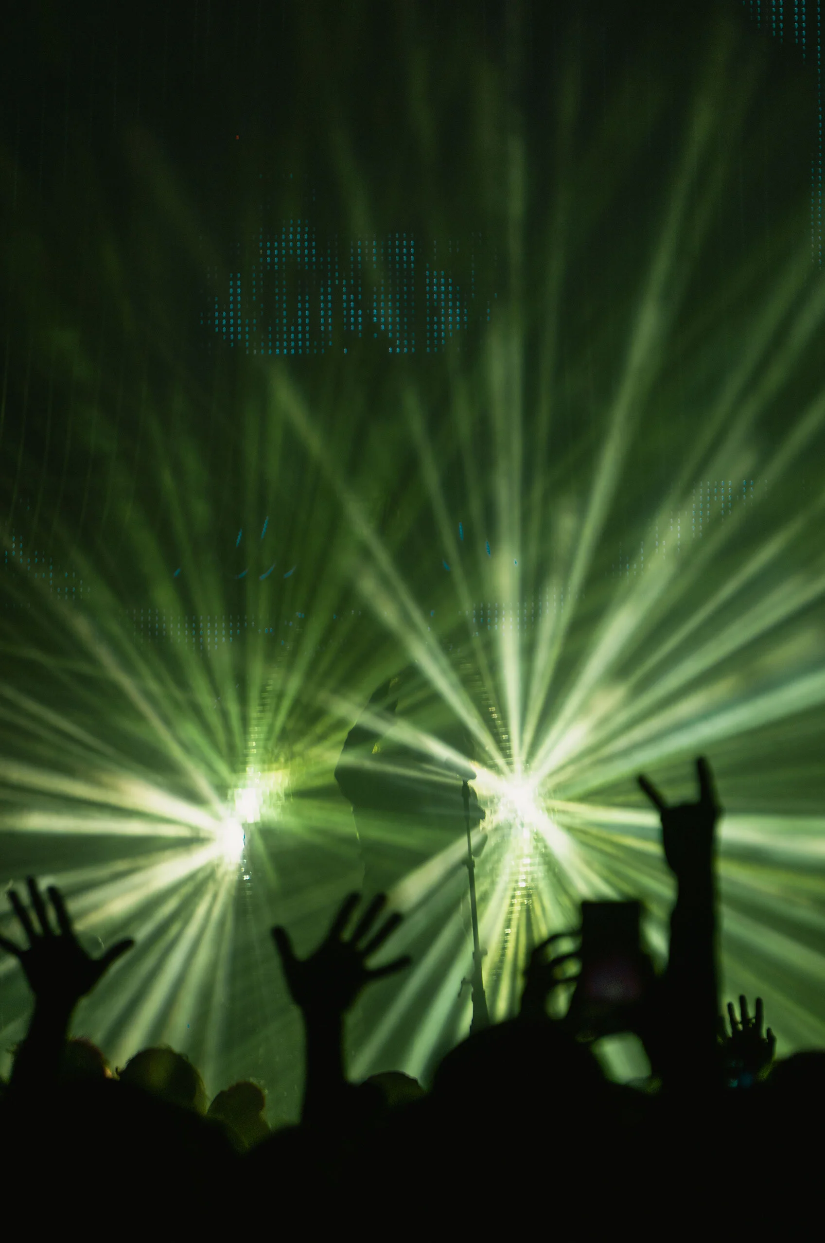 The Flaming Lip's lead singer and the crowd are silhouetted by rays of green light bouncing off a large disco ball onstage. Ogden, Utah.