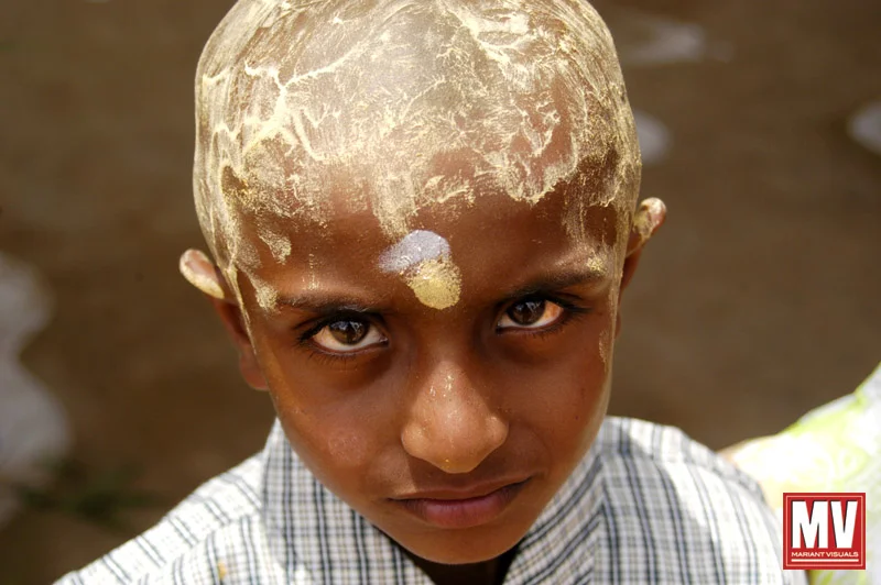 A young boy with crushed, dried flowers turned into a paste atop his head is seen at a firewalking festival at a small village in the Nilgiris region of Tamil Nadu, India.