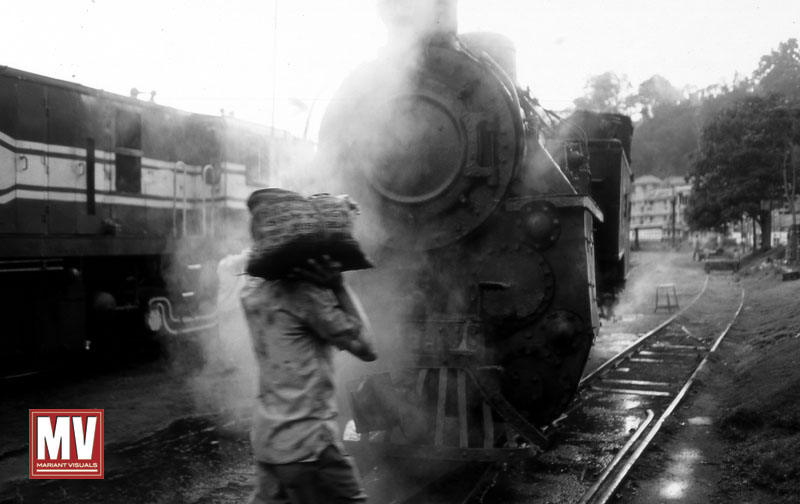 A worker carries a supply bag to a steam train awaiting departure in Udagamandalam (Ooty), India.