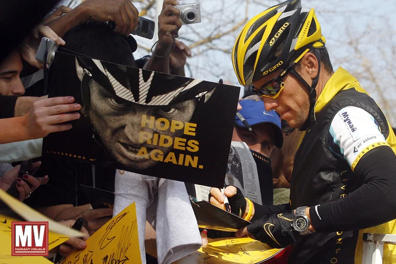 Lance Armstrong signs posters for the fans in Merced, Calif., prior to the start of the fourth stage of the Tour of California cycling race. (AP Photo/Michael A. Mariant)