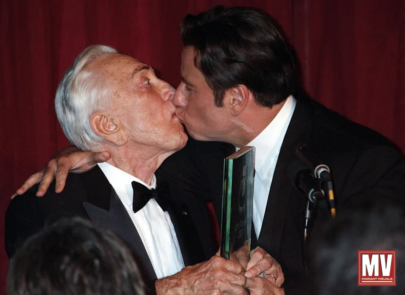 Actor John Travolta kisses fellow actor Kirk Douglas following the presentation of the Santa Barbara International Film Festival's Kirk Douglas Award for Excellence in Film to Travolta