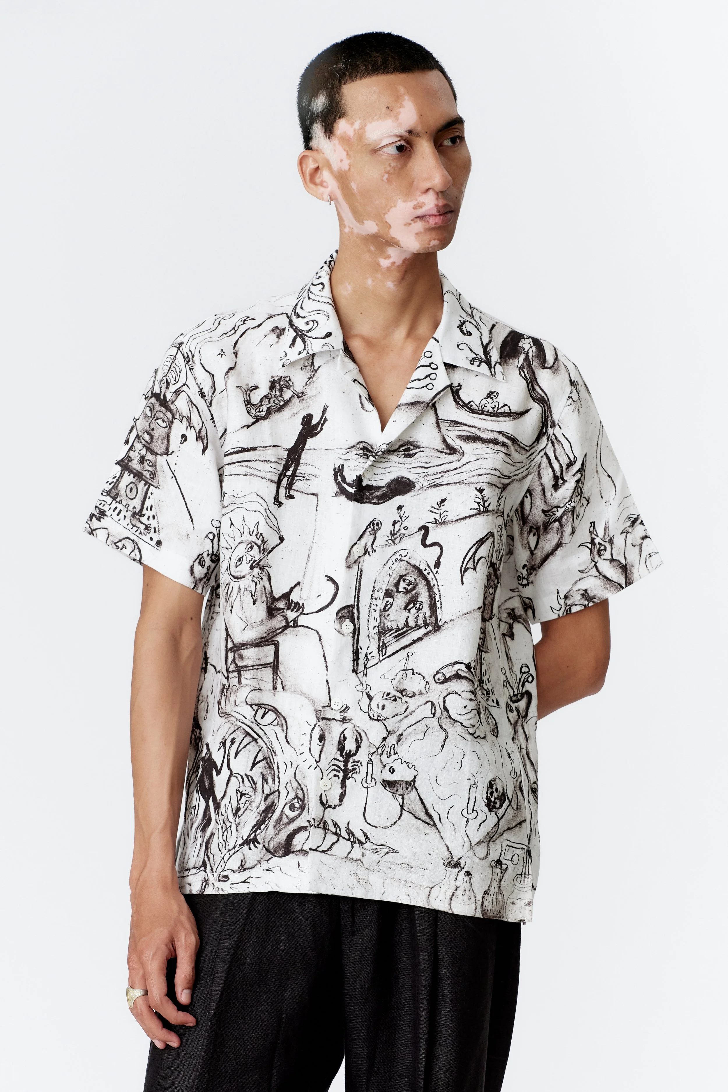 Close-up of ALCHEMY shirt front panel with intricate charcoal sketches of Mercurius, three-headed dragon, and alchemical symbols