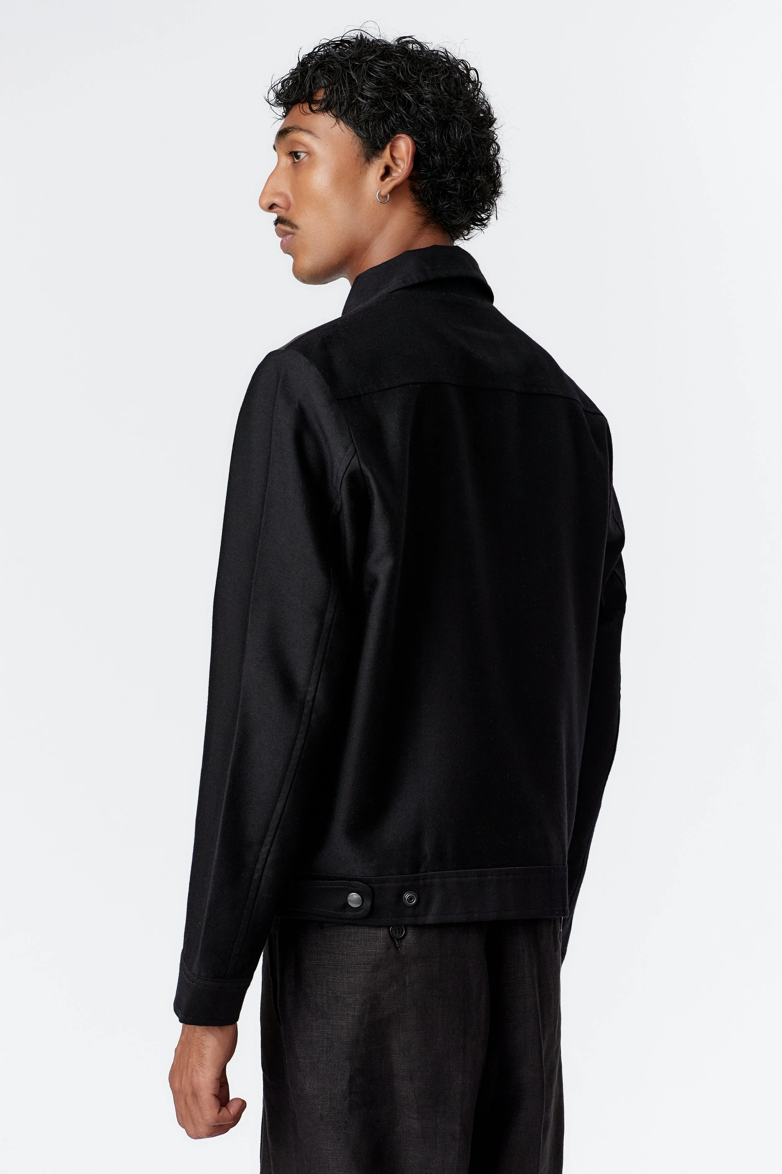 Rear side view close-up showing smooth black fabric on back and sleeves, highlighting contrast with front panel art