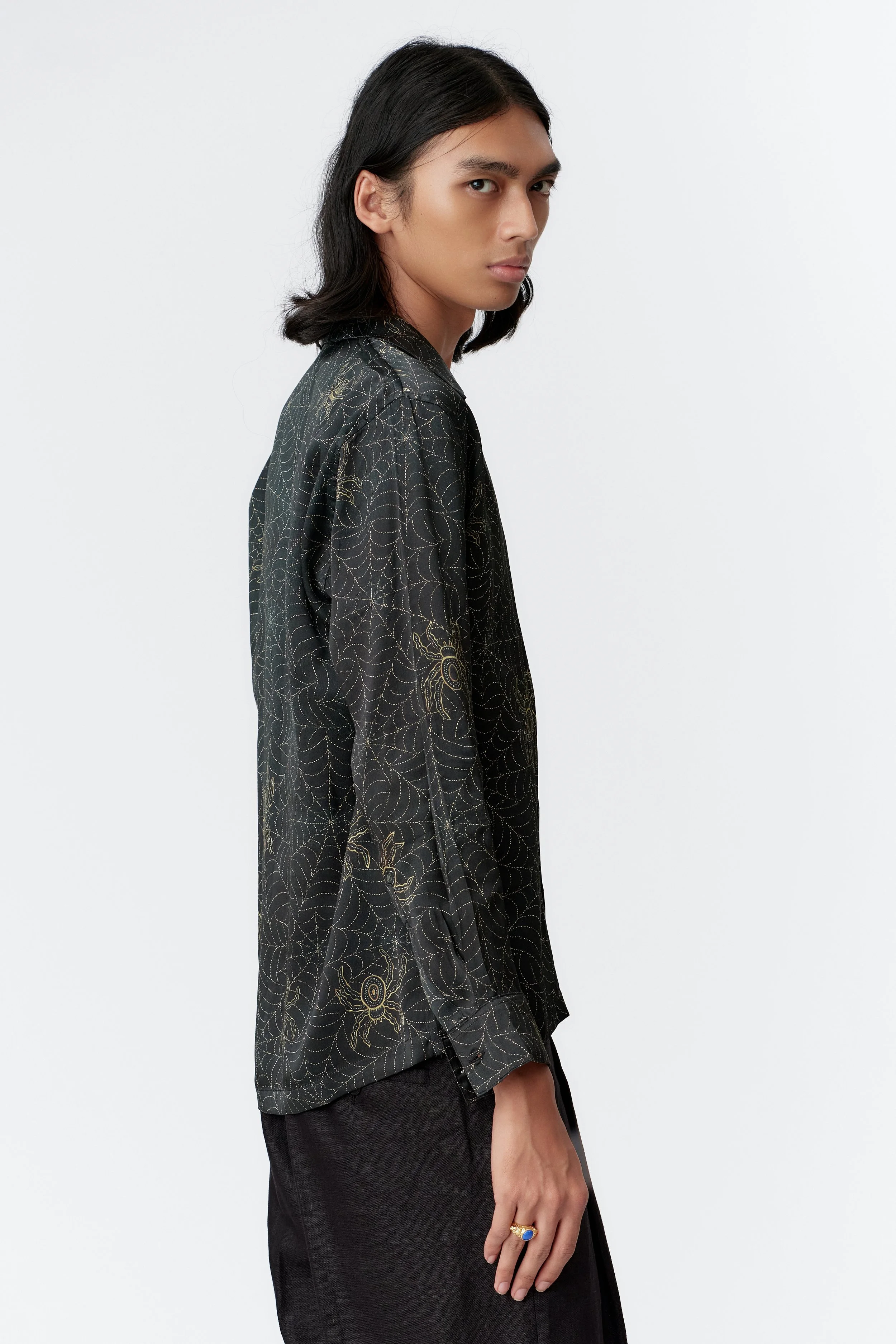 Long sleeve detail of Spiderweb Indigo silk shirt with mother of pearl buttons and intricate web pattern.
