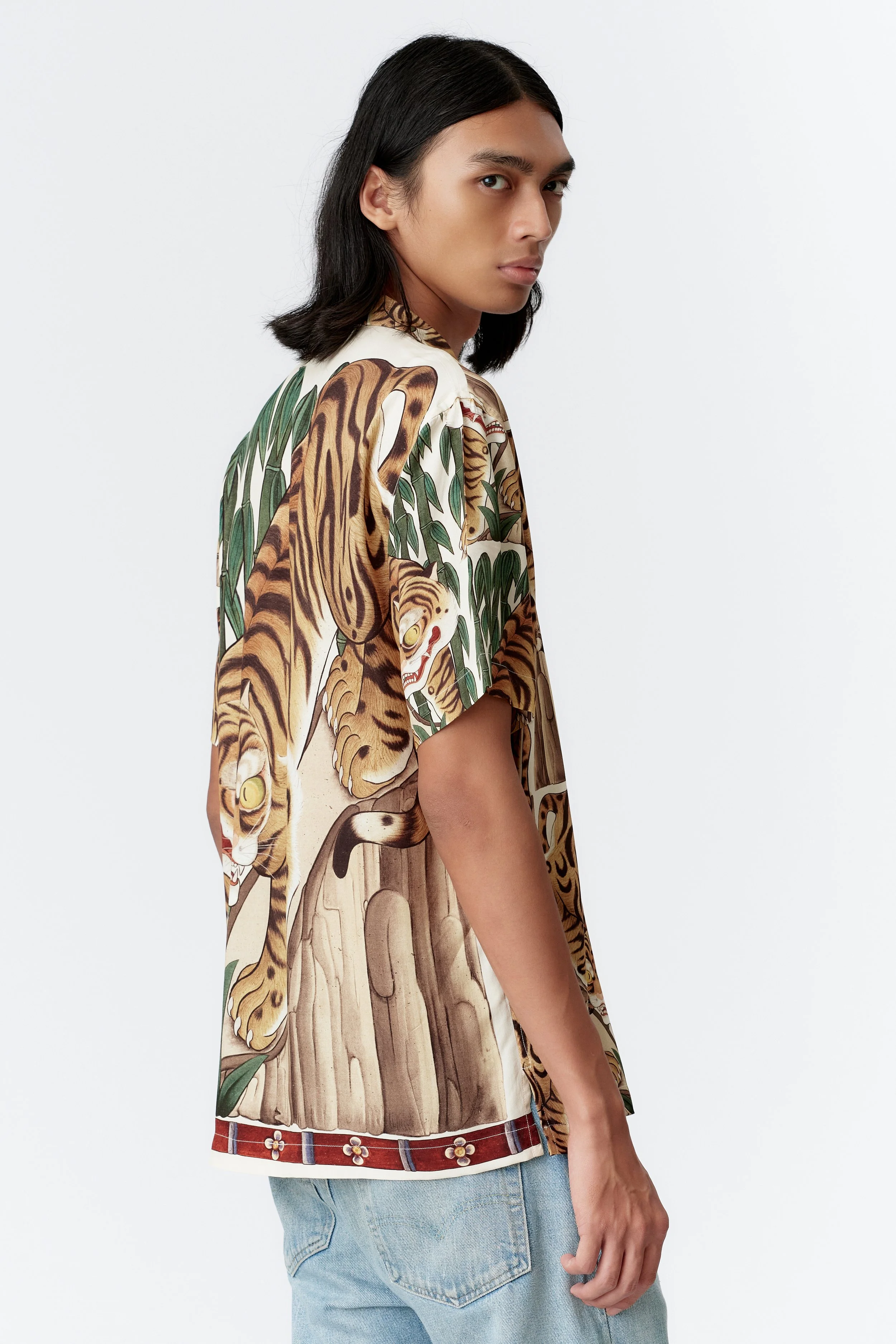 Side profile of model wearing Tiger cream premium rayon shirt with straight hem