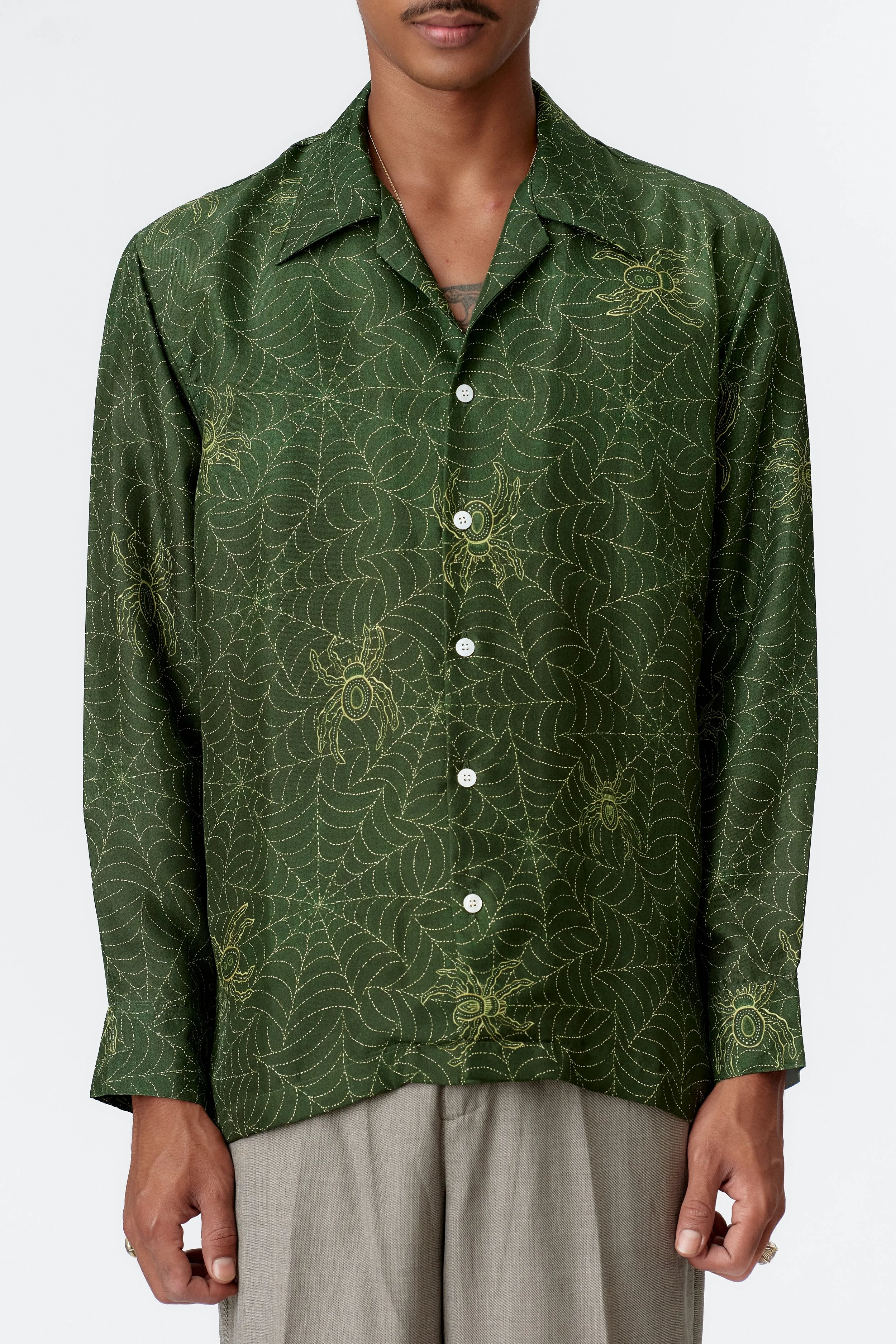Close-up detail of gold spiderweb pattern in batik-style pointillism on green fabric