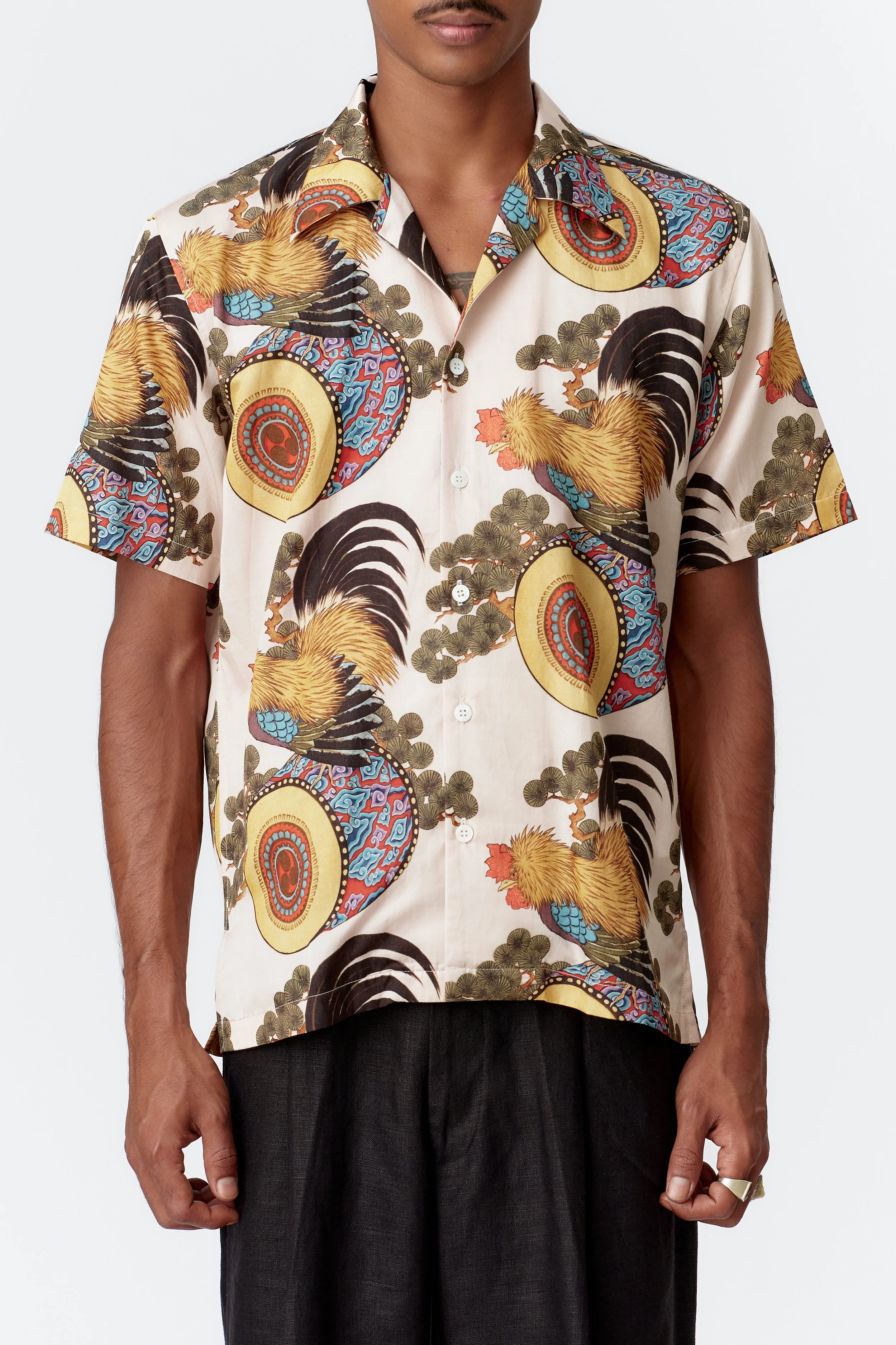 Close-up front detail of rooster perched on ornate drum with swirling cloud motifs