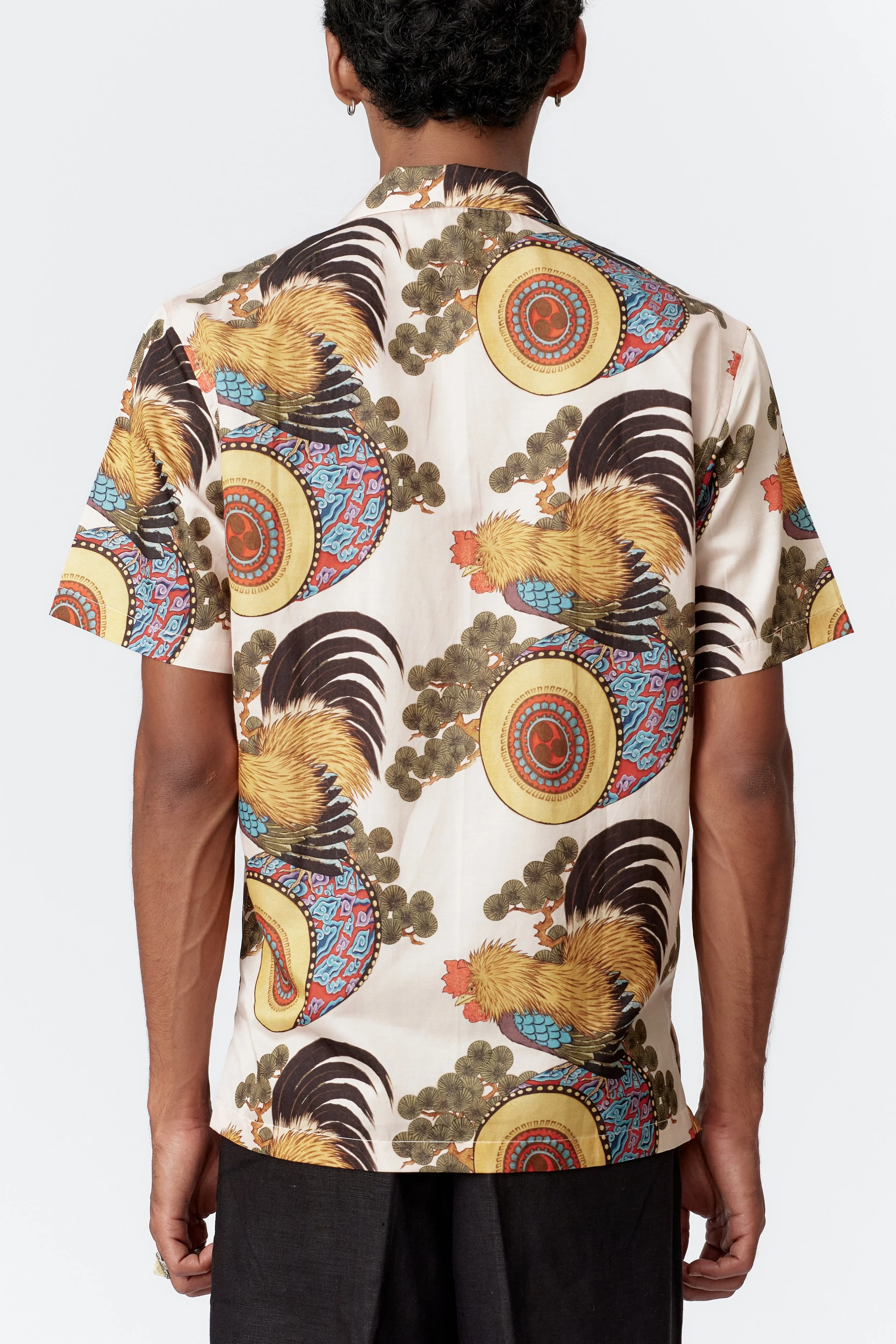 Back view of Rooster Drum cream shirt featuring pine boughs and decorative pattern artwork