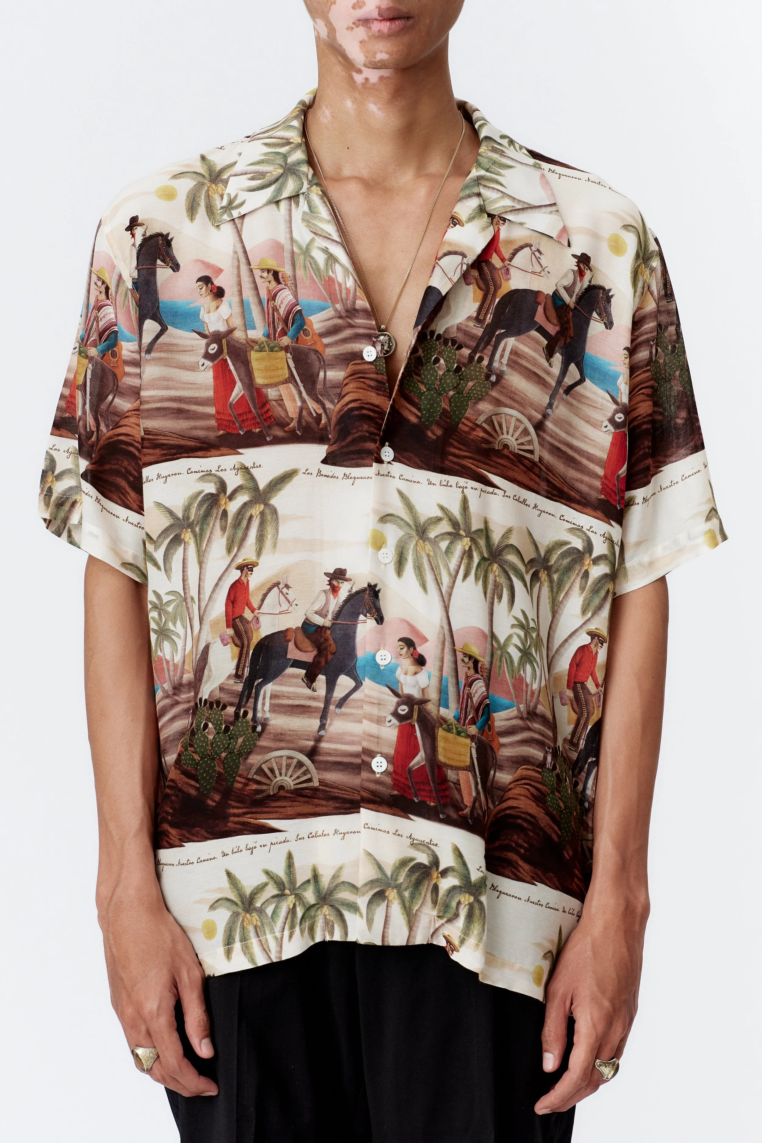 Close-up detail of repeat cowboy, farmer, and donkey illustration on off white silk rayon fabric