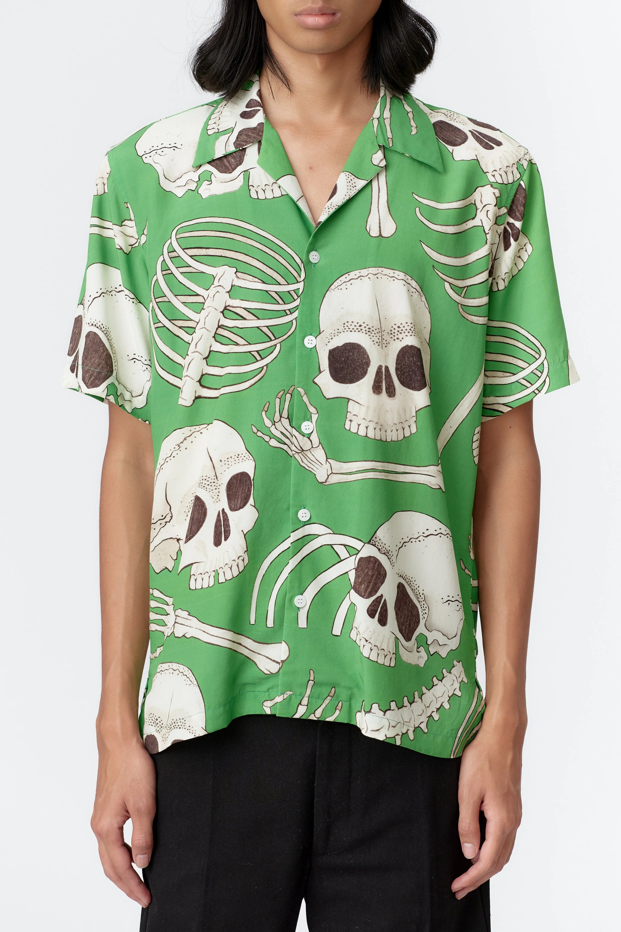 Close-up front detail of white skull and bone artwork on vibrant green modal fabric