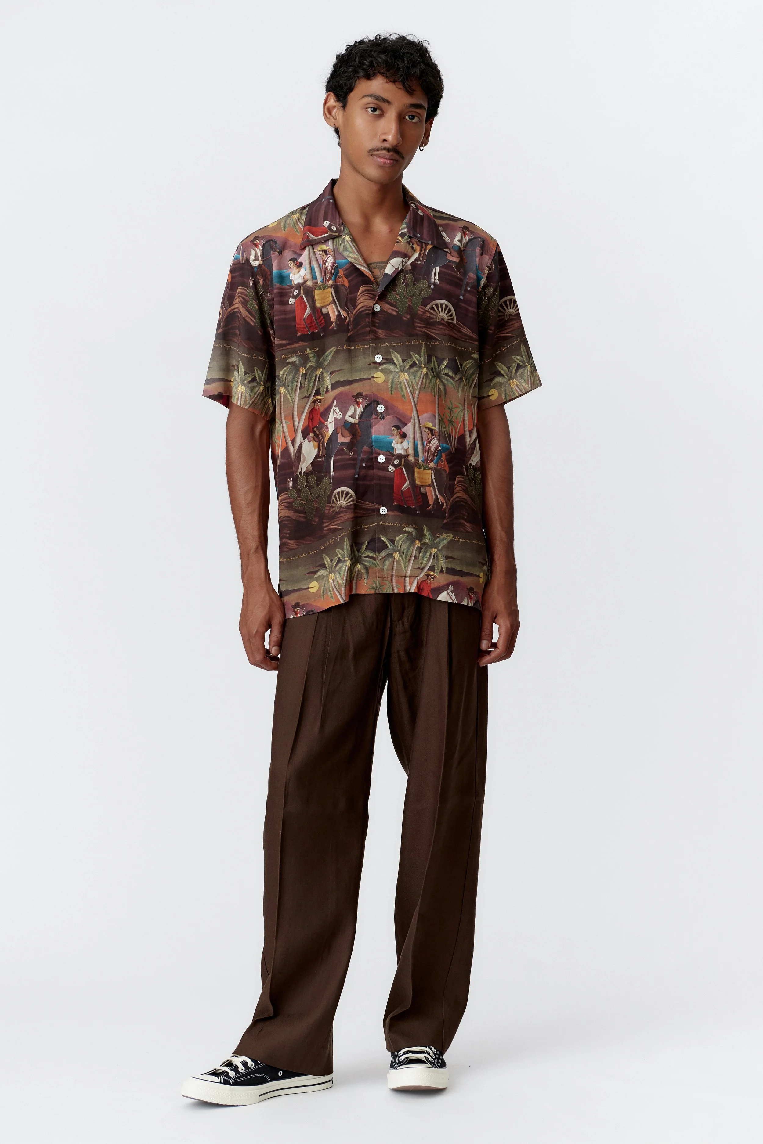 Full front view of Bandito Repeat Bottle Green short sleeve shirt featuring all-over surreal desert western artwork on deep green fabric