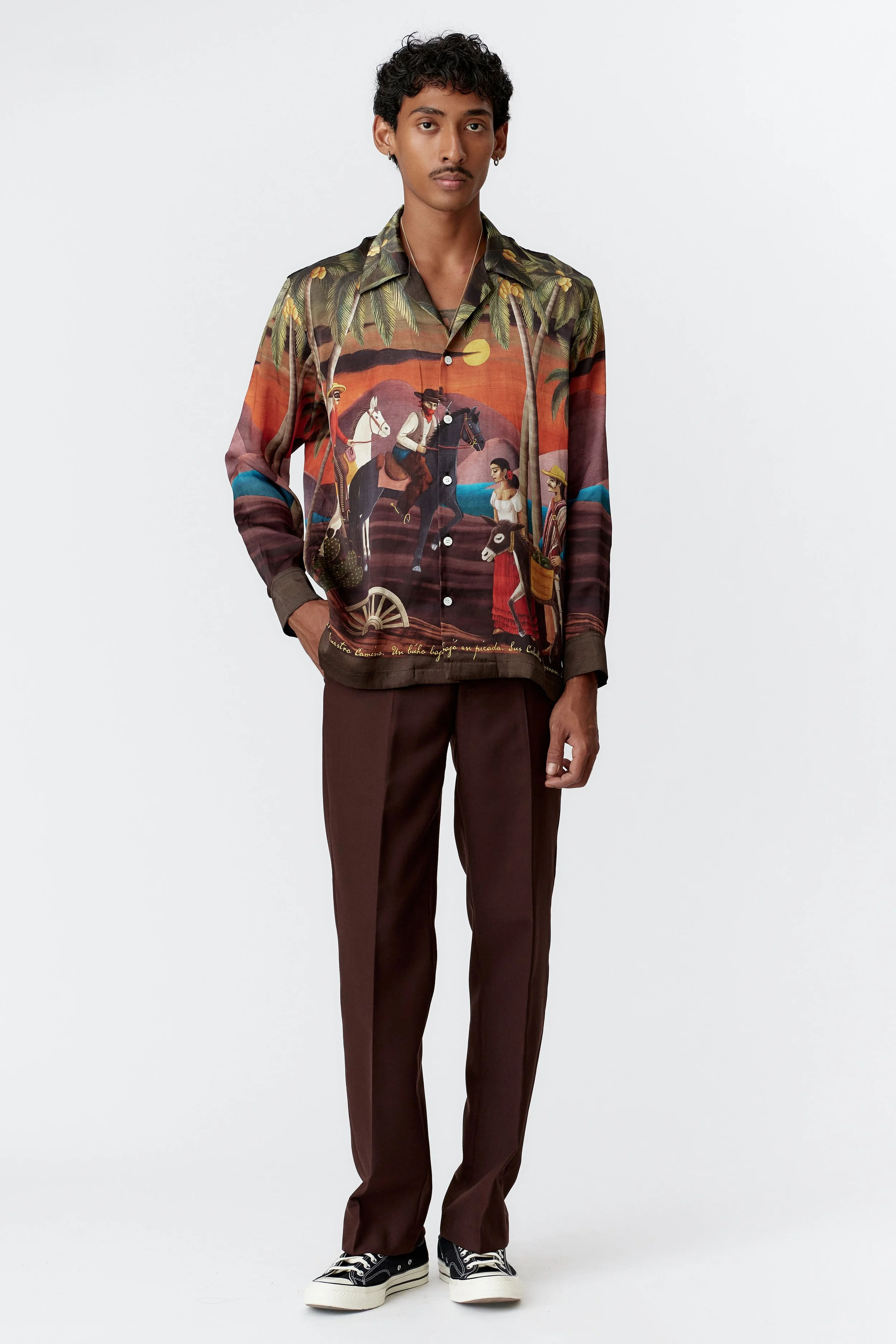 Model wearing Bandito Bottle Green 100% silk satin long sleeve shirt highlighting relaxed luxury fit and cinematic Western artwork.