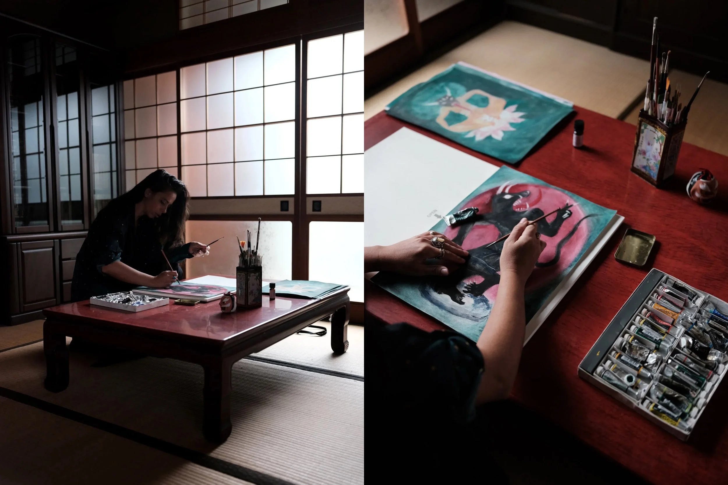 A woman painting traditional Japanese style artwork at a low table in a dimly lit room with shoji screens.