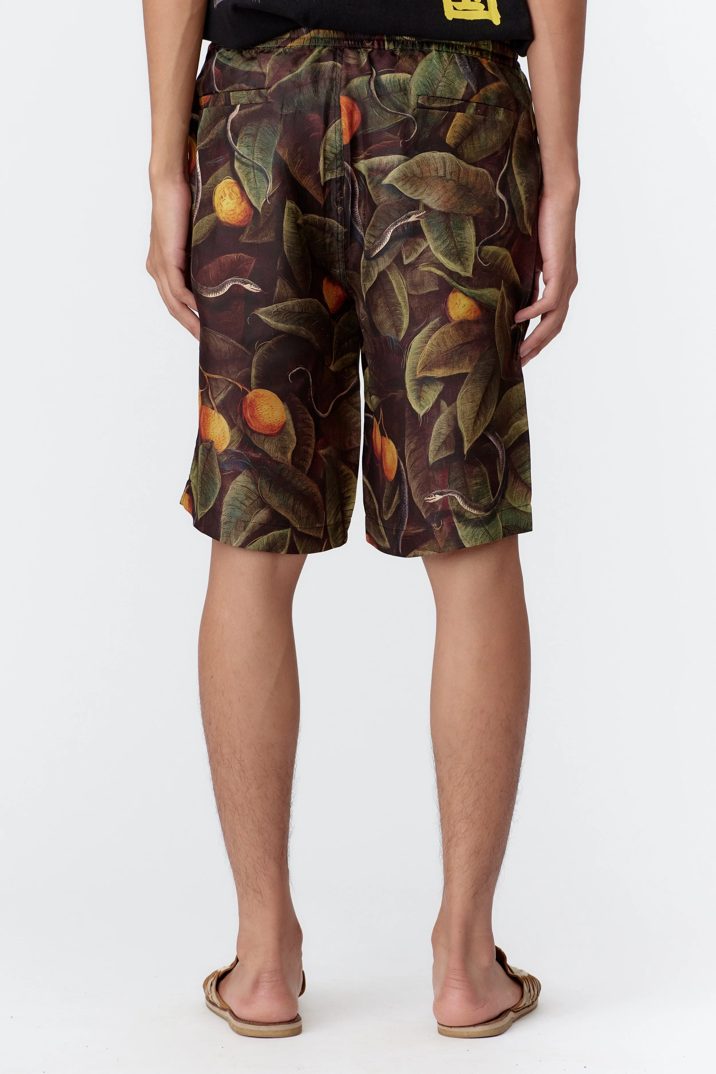 Back angle of model wearing Snaker limited edition silk board shorts highlighting drape and artwork placement