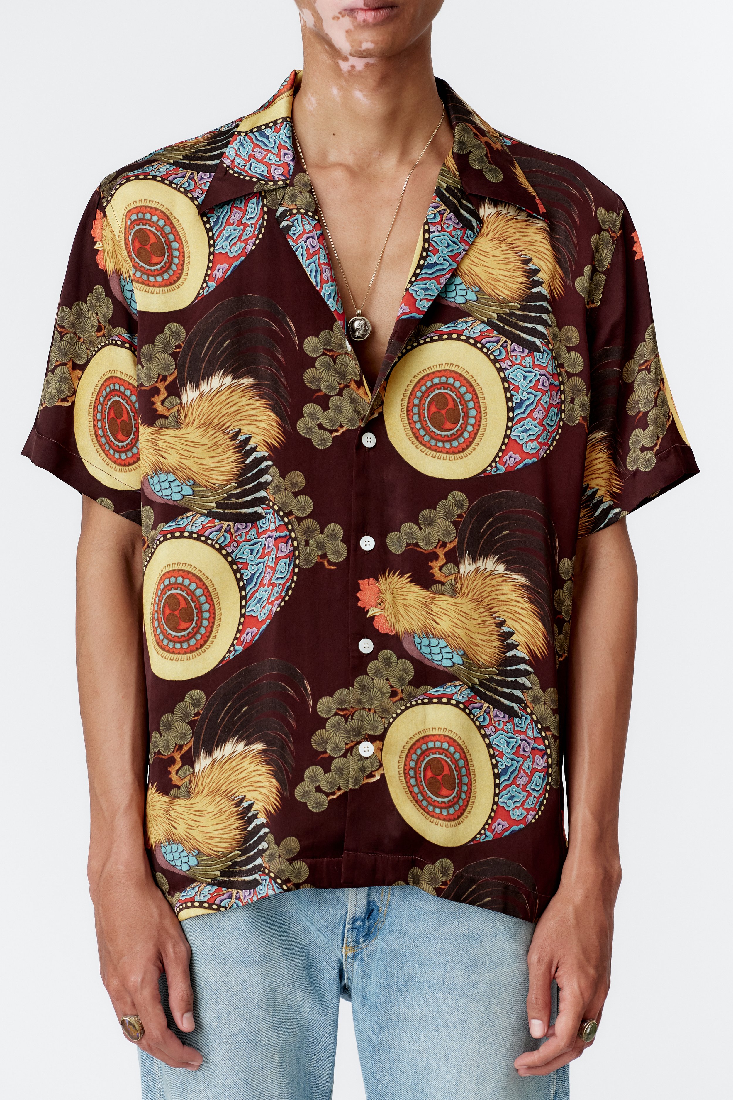 Close-up of silk satin fabric featuring multicoloured rooster illustration.