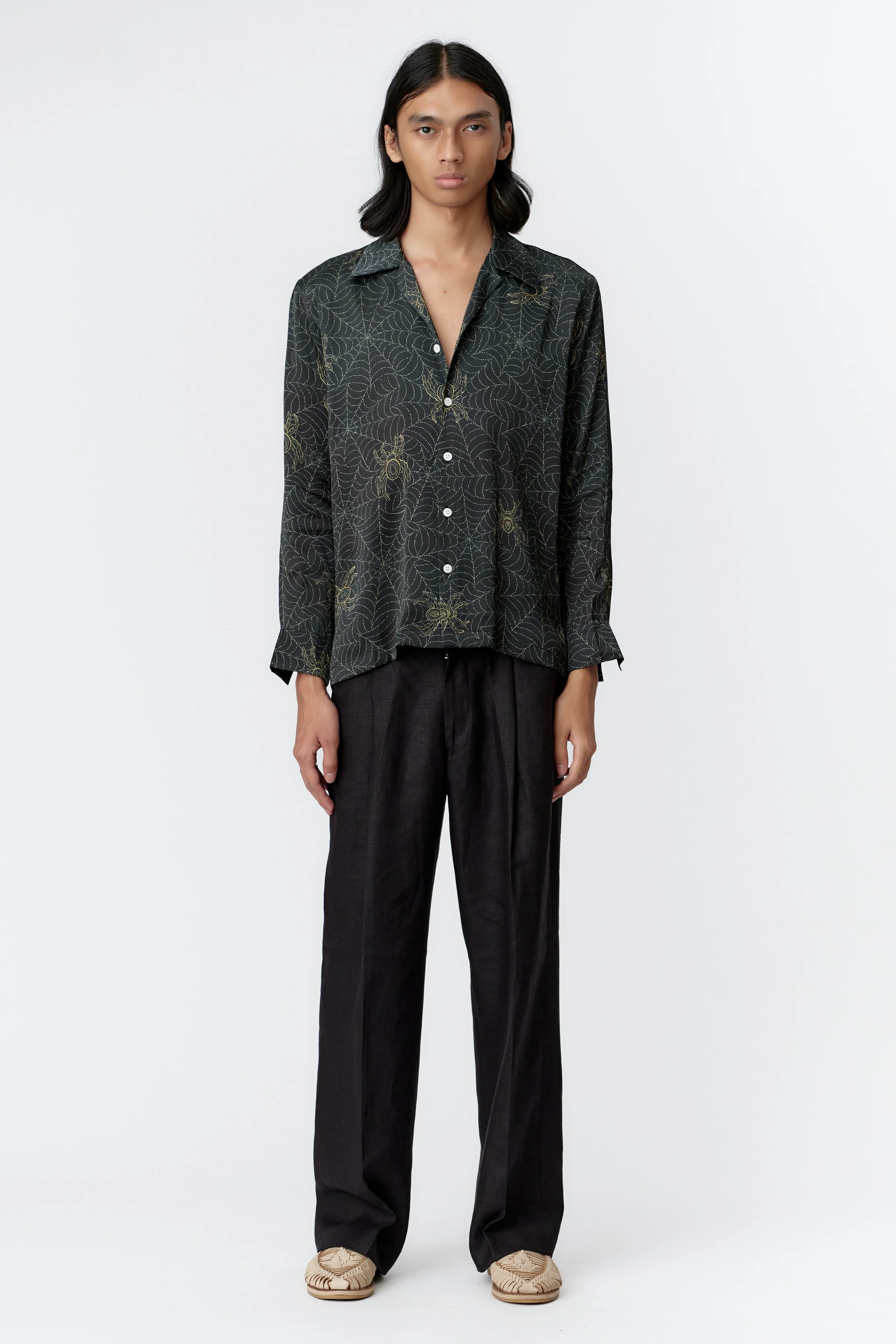 Model wearing Spiderweb Indigo 100% silk satin long sleeve shirt highlighting relaxed luxury fit and geometric spider design.