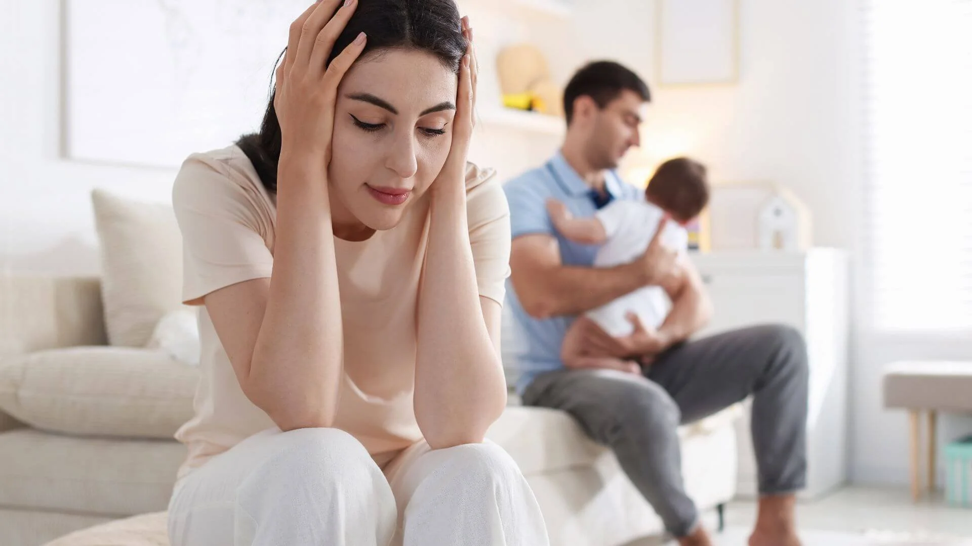 Mother taking a break while dad cares for baby in the background