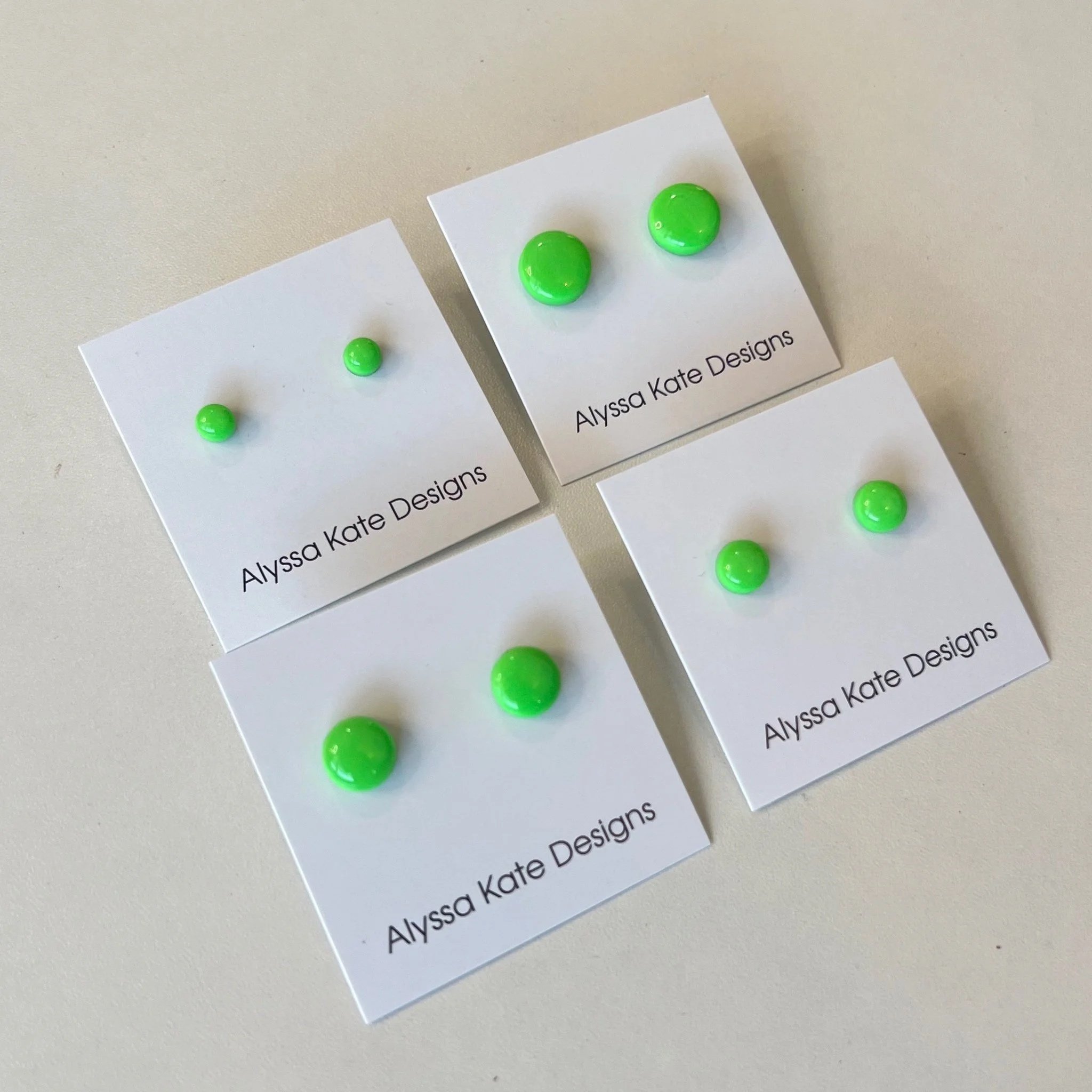 Neon green polymer clay stud earrings displayed in multiple sizes on Alyssa Kate Designs jewelry cards.