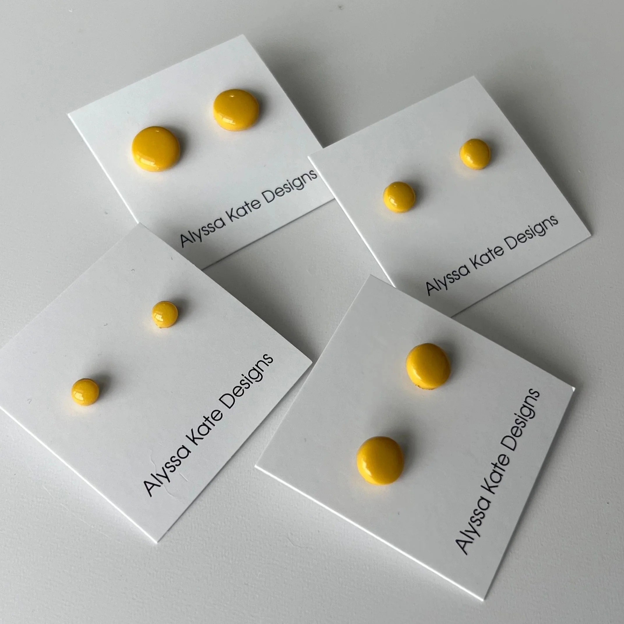 Golden yellow polymer clay stud earrings displayed in multiple sizes on Alyssa Kate Designs jewelry cards.
