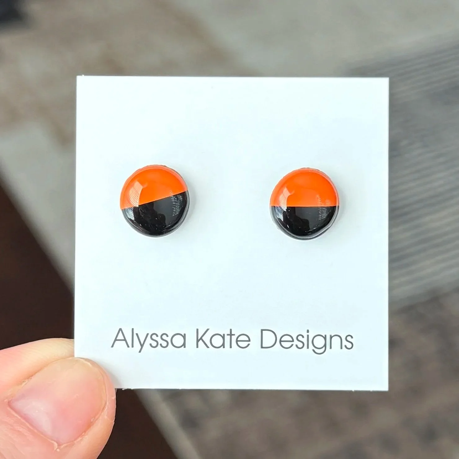 Black and orange two-tone polymer clay Game Day stud earrings on Alyssa Kate Designs card