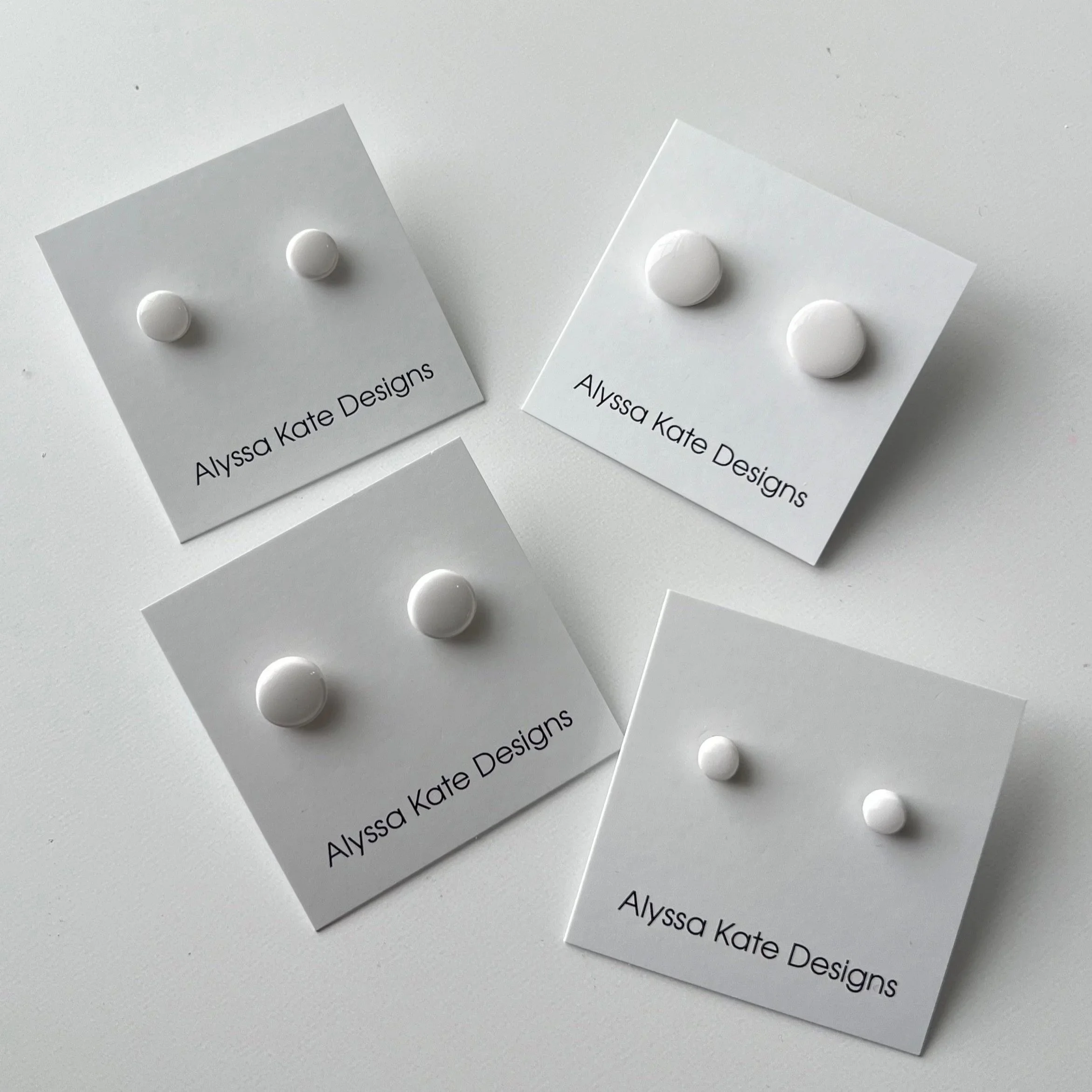 White polymer clay stud earrings displayed in four sizes on Alyssa Kate Designs jewelry cards.