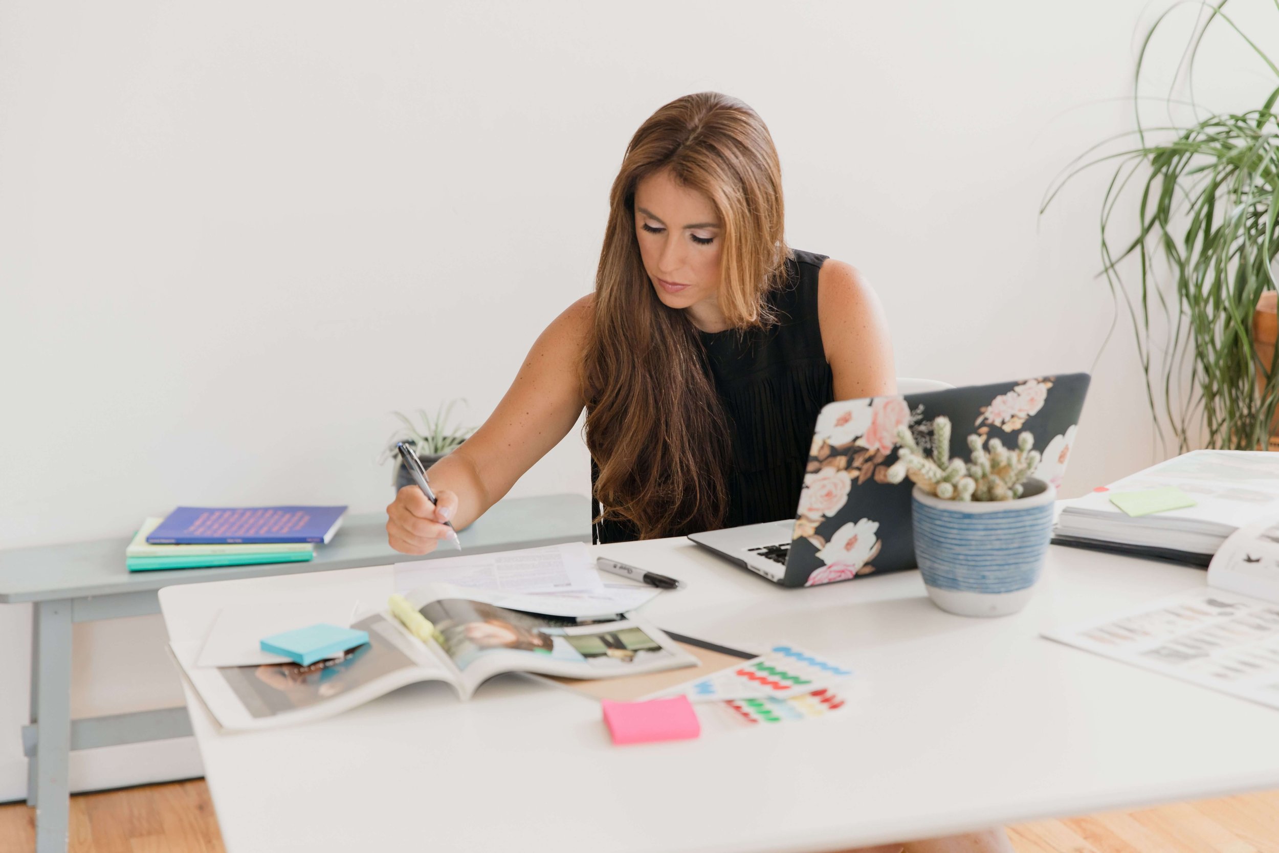 Successful female entrepreneur reviewing notes and planning her finances while building healthier money management systems.