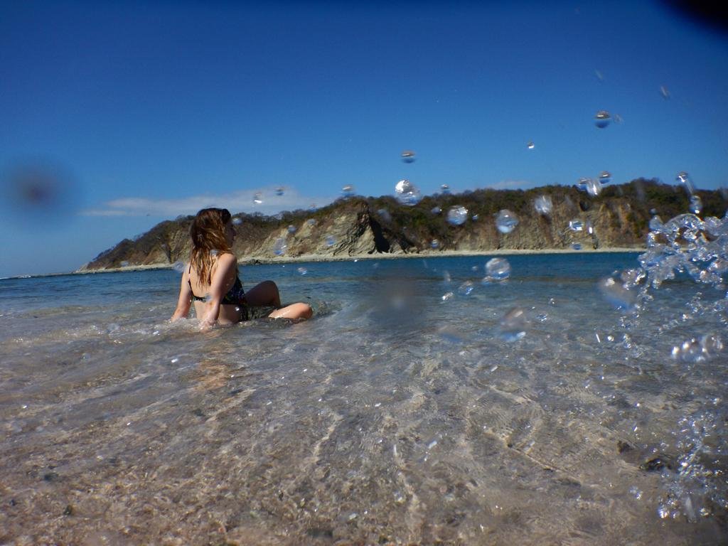 Woman lounging in clear shallow water on a pink island tour in Nosara, Costa Rica.
