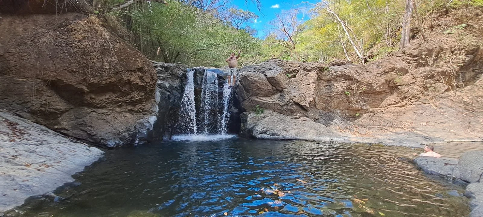 Man jumping off the pilas blancas waterfall in Nosara into the water below.