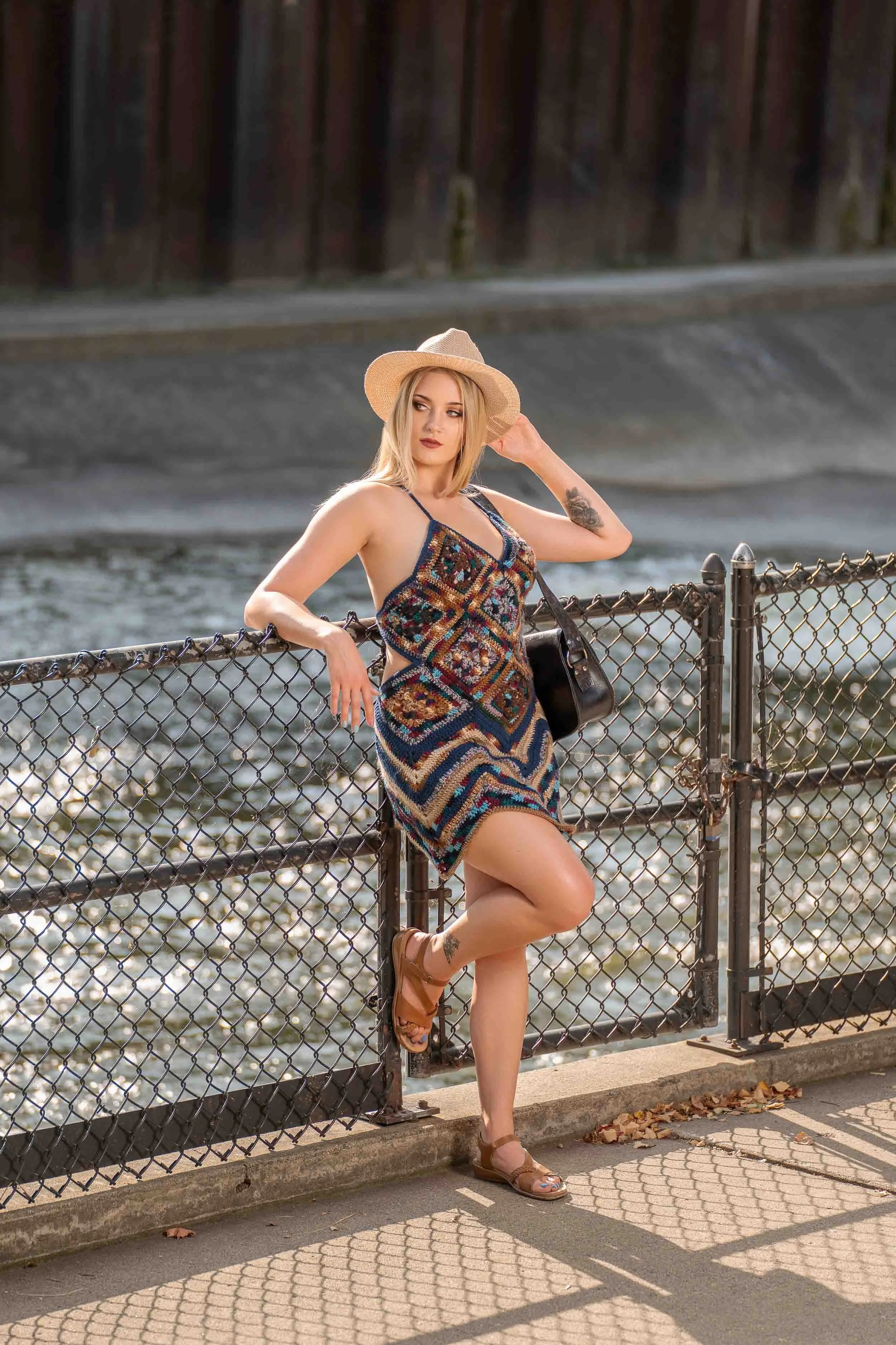 Professional lifestyle fashion photography in South Bend featuring a model in a crochet dress and sun hat posing by the St. Joseph River