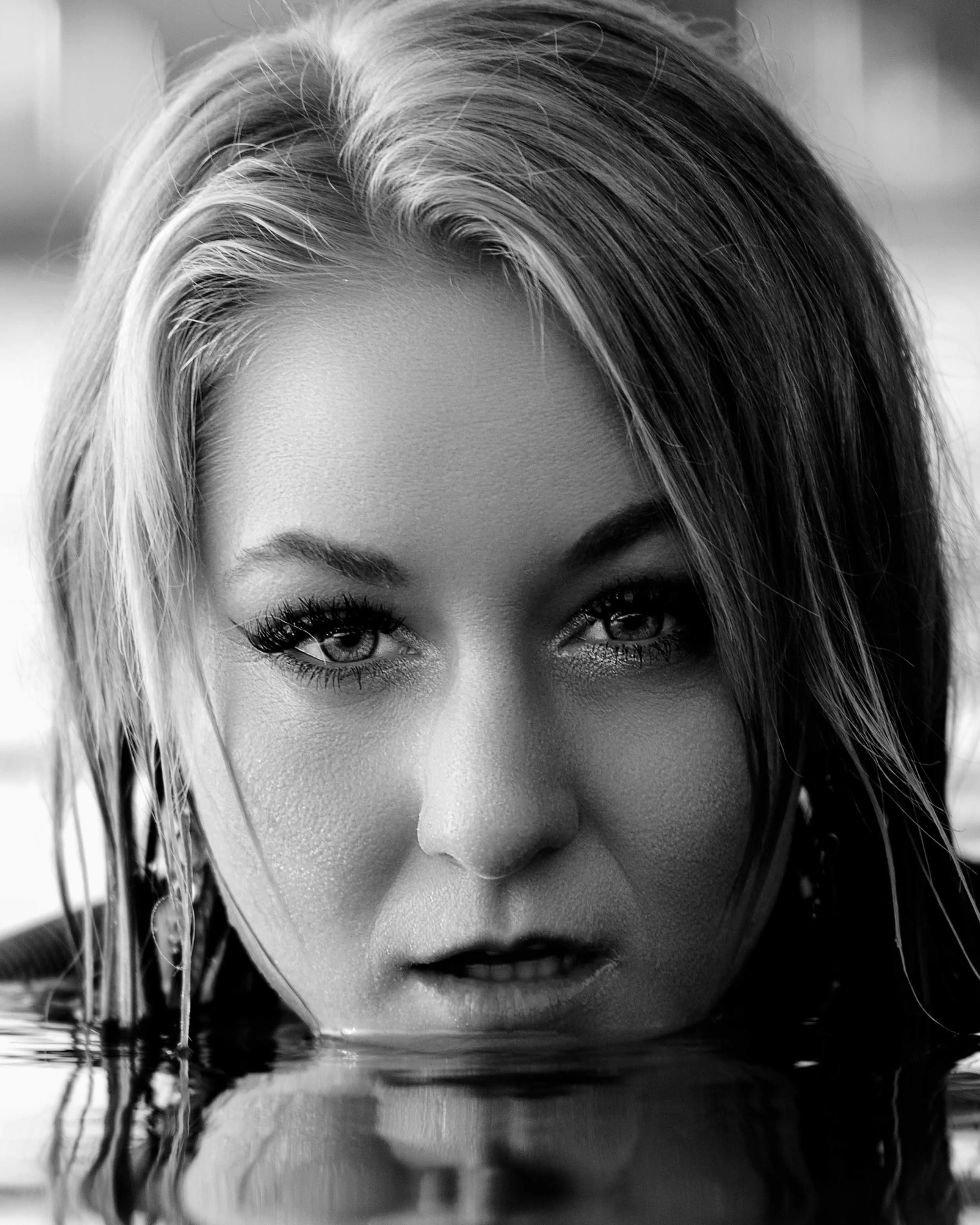 Close-up black and white artistic portrait of a woman’s face partially submerged in water, Michiana creative photography.