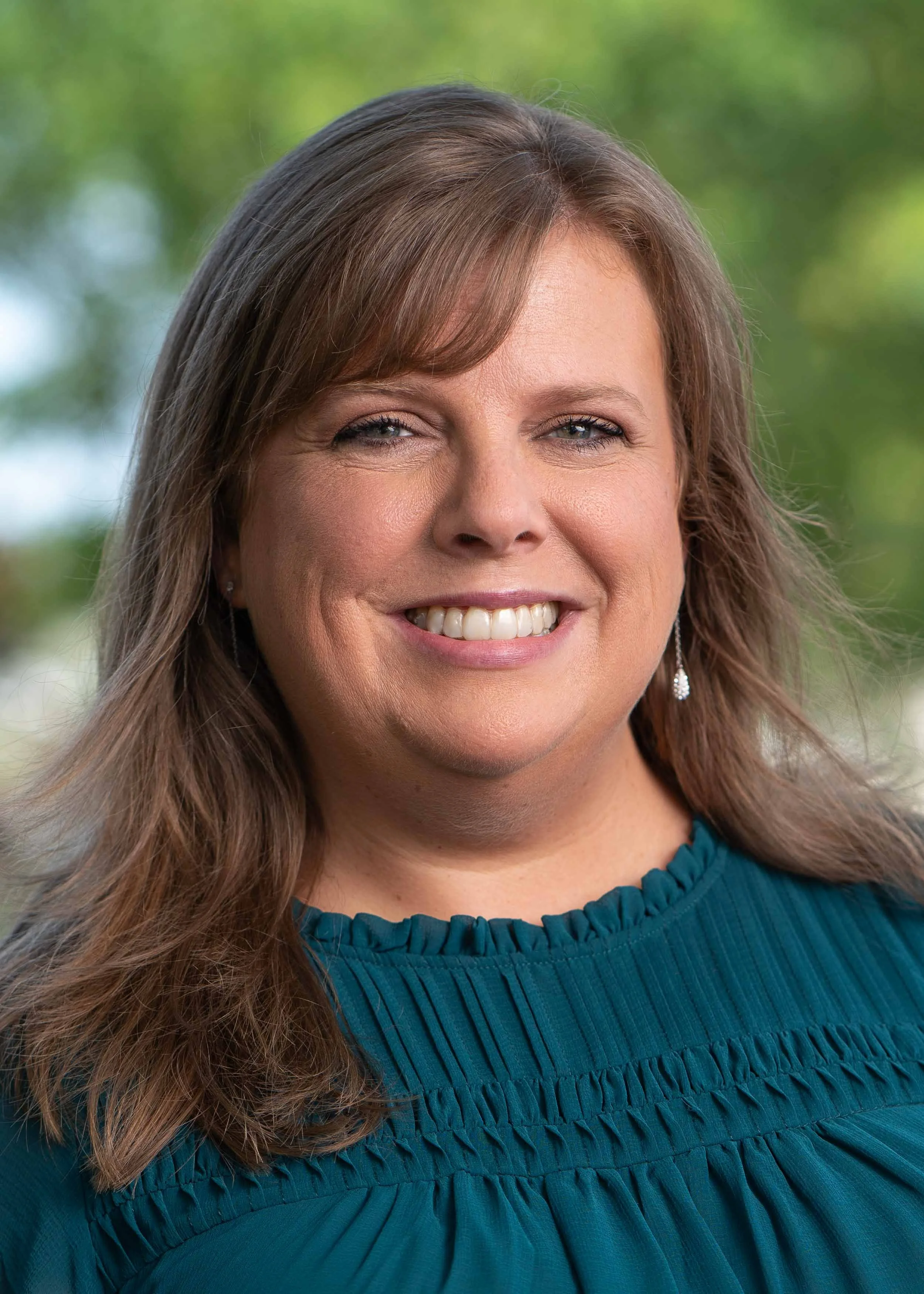 Professional corporate headshot of a smiling woman in a teal blouse; high-quality business portraiture by a South Bend headshot photographer