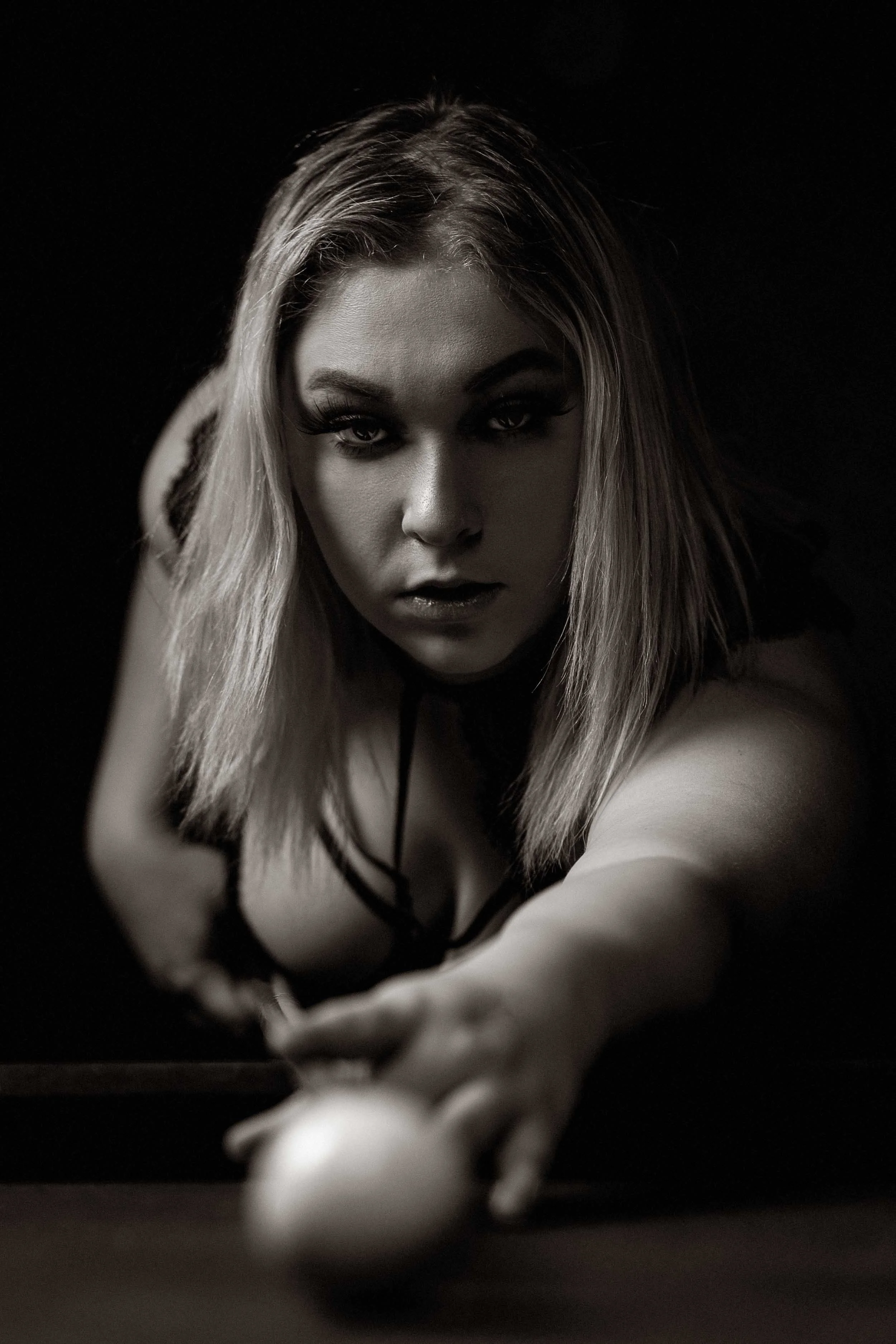 Moody black and white boudoir photography in Michiana featuring a dramatic lifestyle portrait of a woman playing pool.