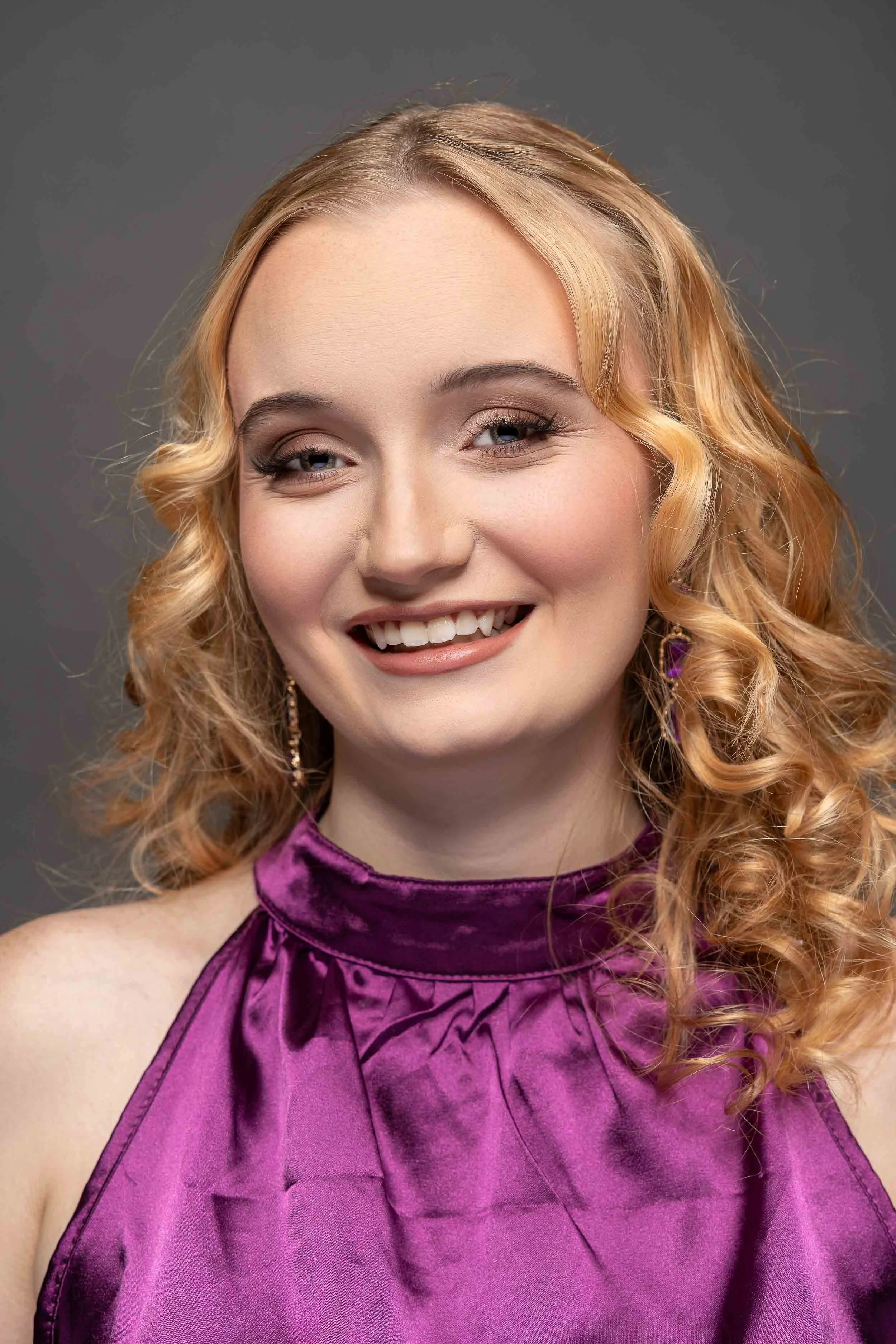 A bright, smiling portrait of a young woman with elegant makeup and golden curls, professional portraiture by a South Bend photographer