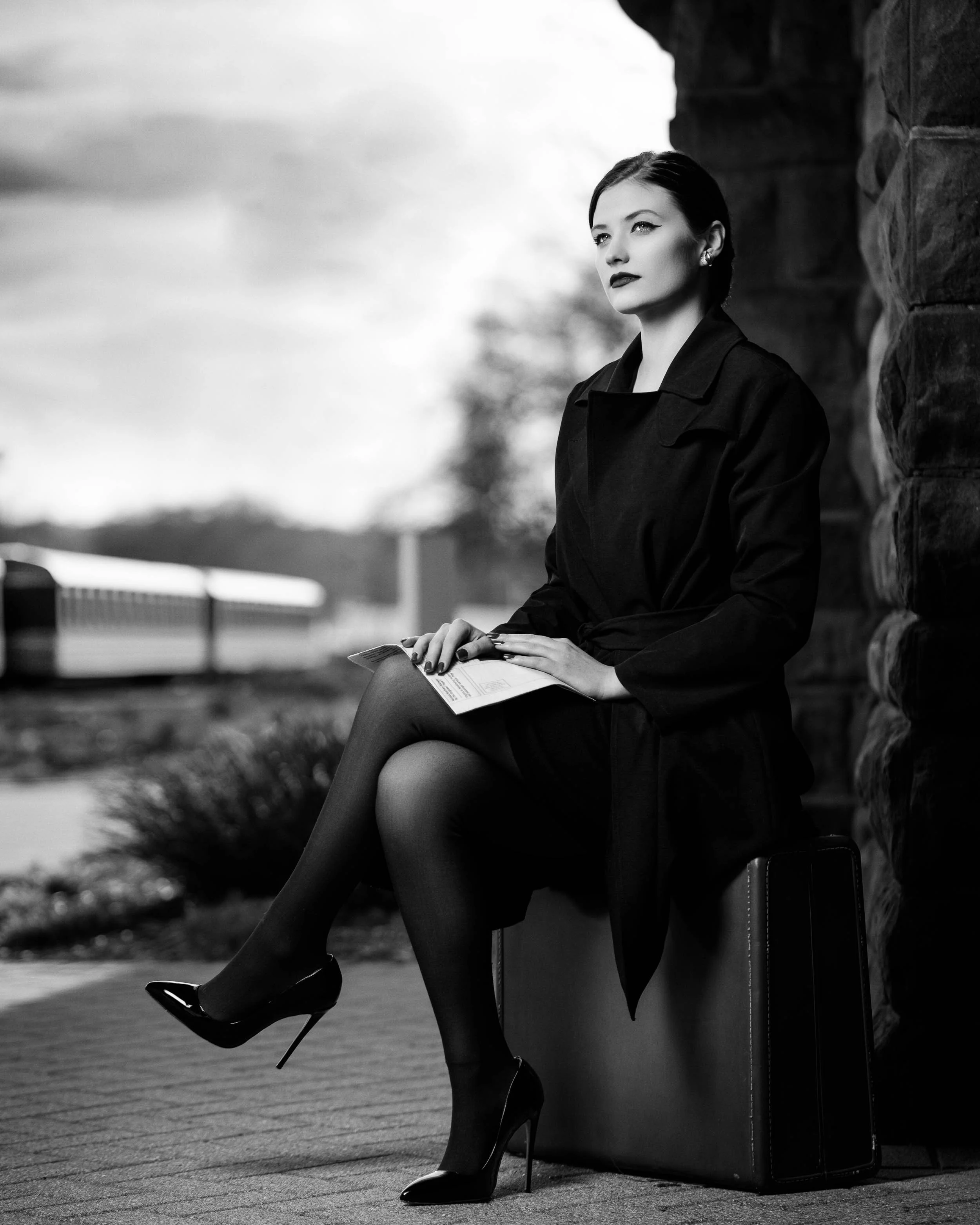 Moody black and white fashion photography of a woman with a suitcase at the Elkhart train station, captured by James Russell Photography.