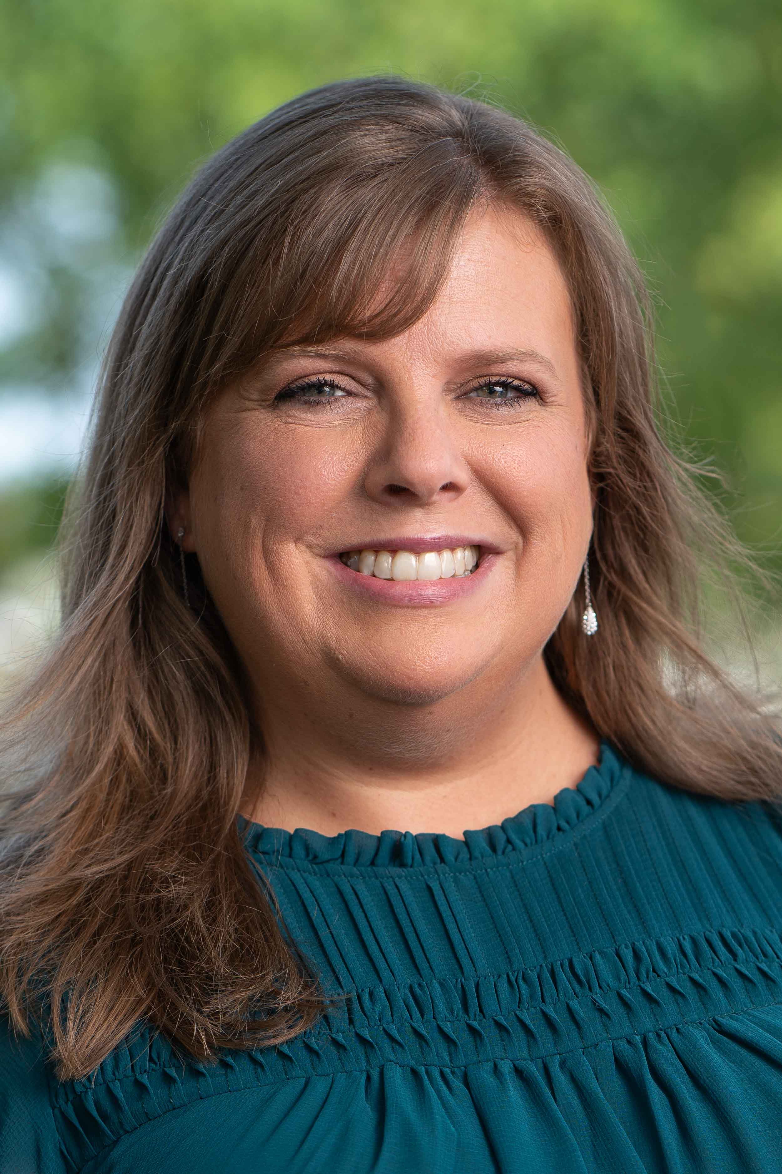 Professional corporate headshot of a smiling woman in a teal blouse; high-quality business portraiture by a South Bend headshot photographer
