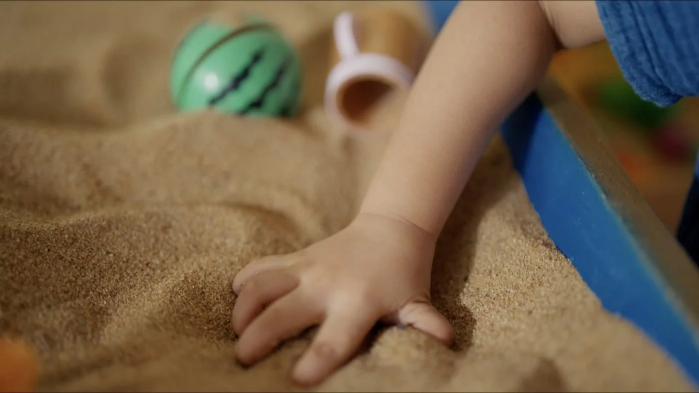 Child’s hand exploring sand tray materials during a play therapy session focused on sensory expression and emotional regulation.