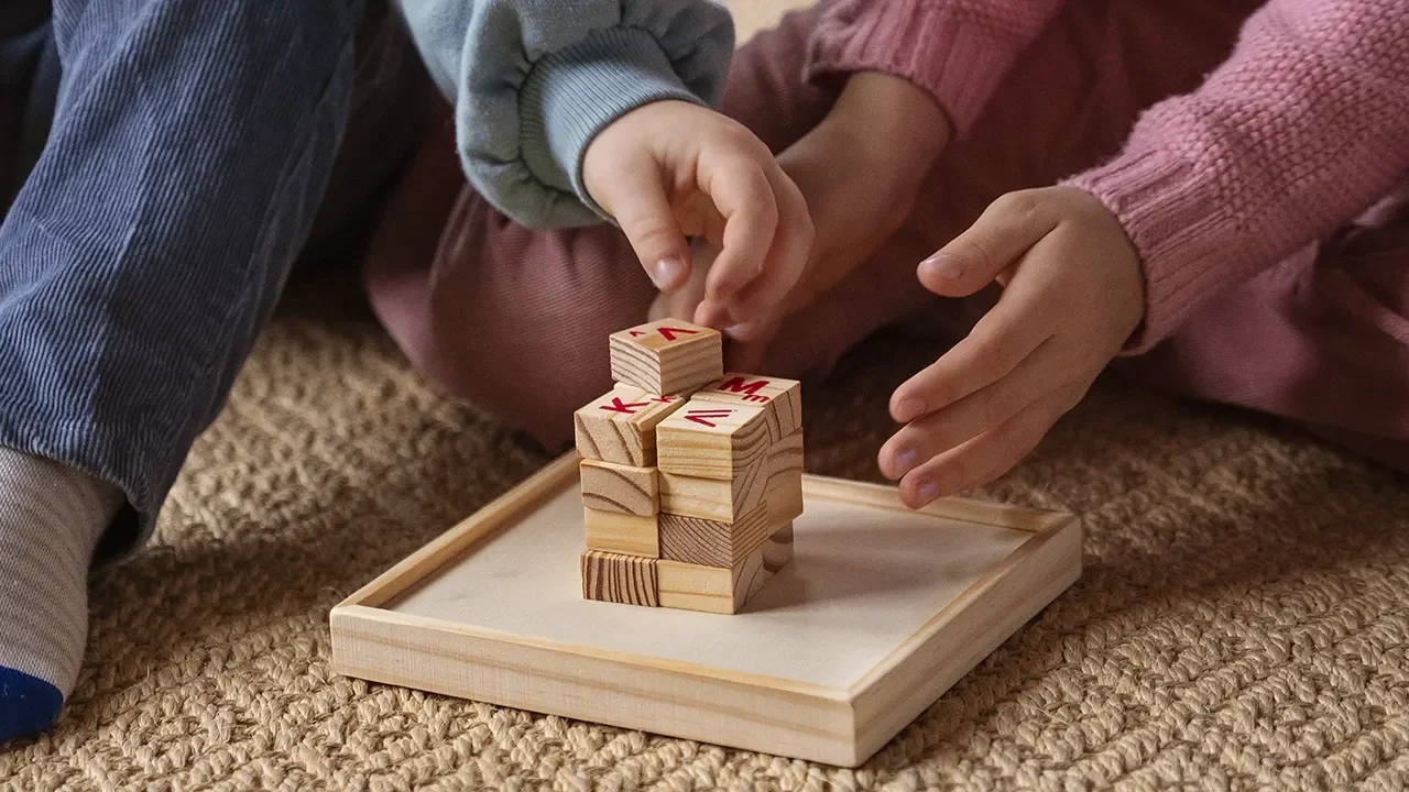 Children playing a wooden block game together, illustrating cognitive development, focus, problem-solving, coordination, and social interaction through board and card games.