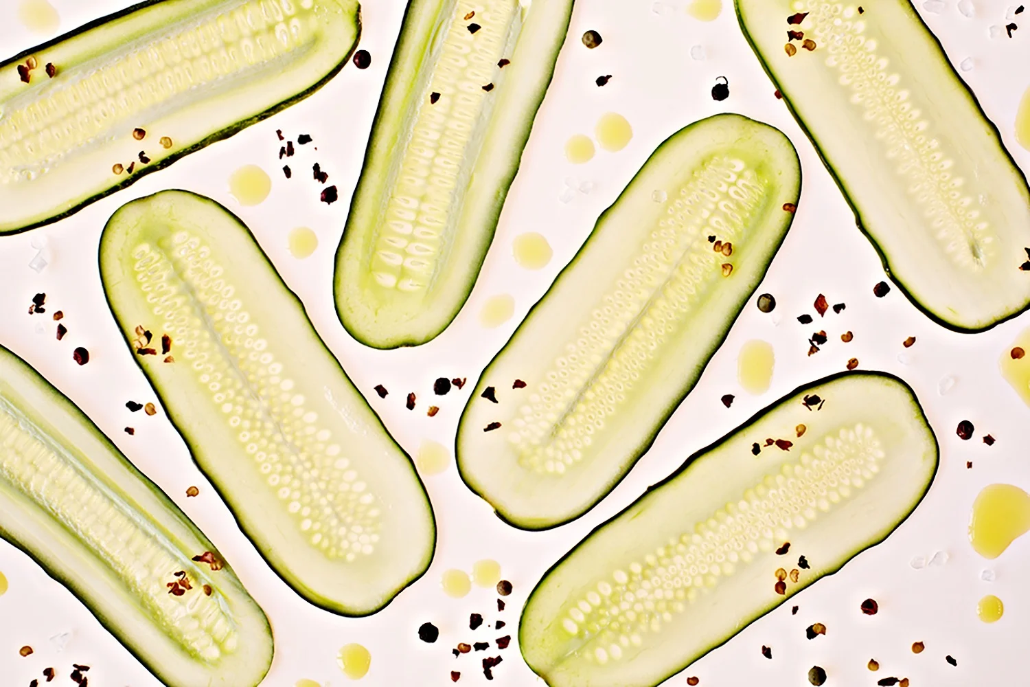 Overhead shot of thin sliced pickles with spices on white