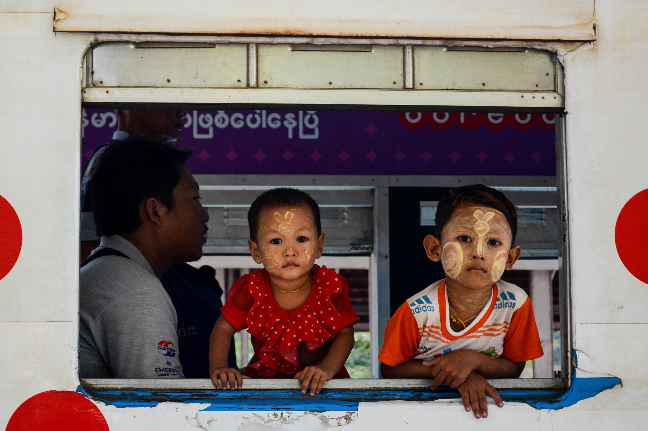  Two children ride the Yangon Circle Line train with traditional thanaka paint on their faces. (Image:  Fran Cresswell ) 