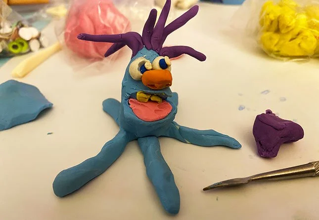 Upchuckle Education Cartoon Camp After School Program for November is Sculpting Expressive Characters. The image is a clay sculpture of a happy looking octopus-like muppet character