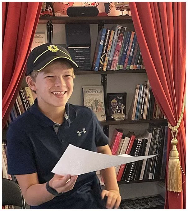 Upchuckle Education provides confidence to children. The photo is of a happy boy, proudly holding his art work at Cartoon Camp