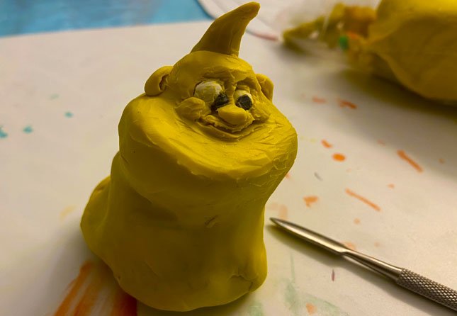 Upchuckle Education Cartoon Camp After School Program for November is Sculpting Expressive Characters. The image is a clay sculpture of a happy looking octopus-like muppet character