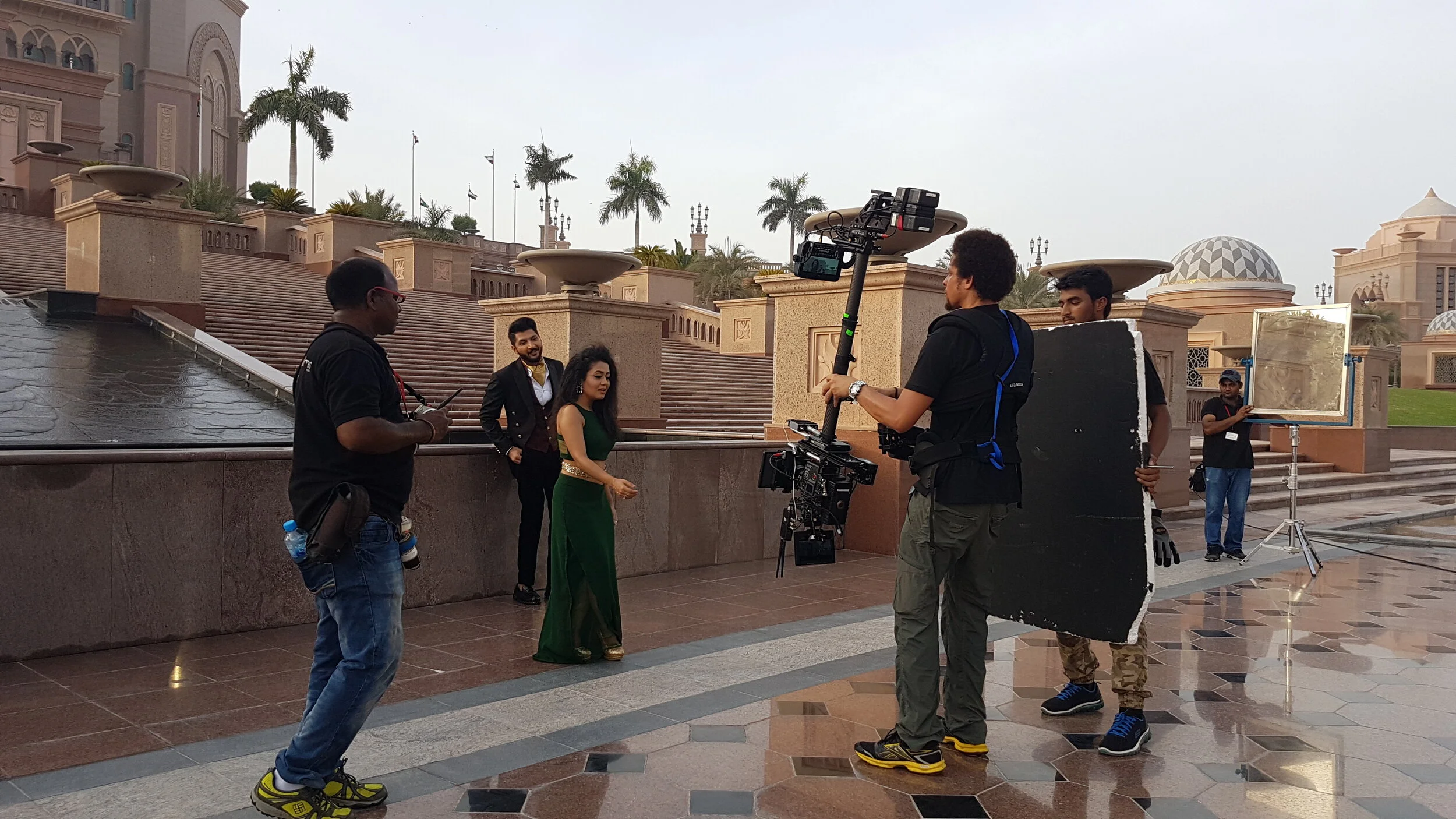 Steadicam operator and crew filming performers on an outdoor set