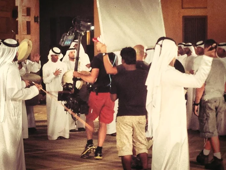 Camera operator filming performers and drummers indoors