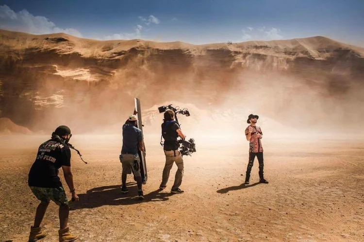 Camera operator and crew working in a desert landscape