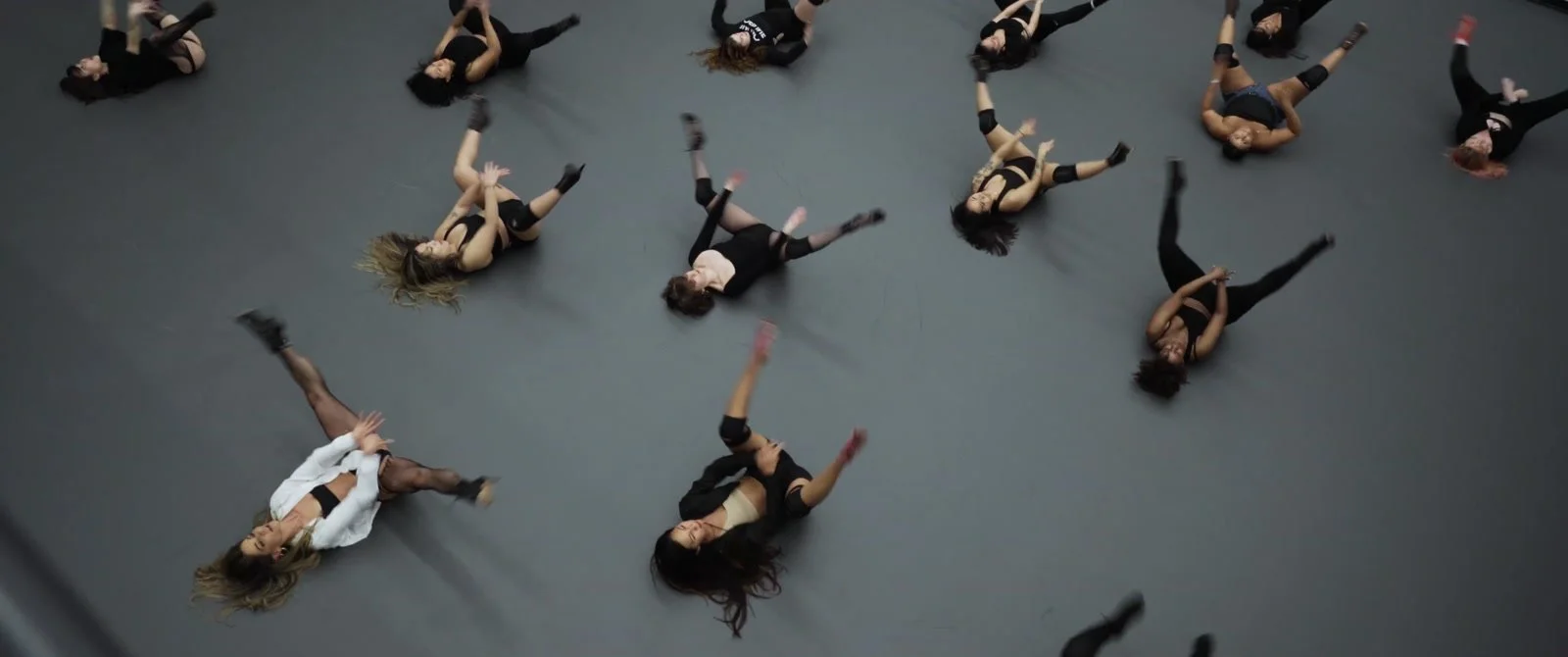 An overhead view of dancers extending their arms and legs across a studio floor.