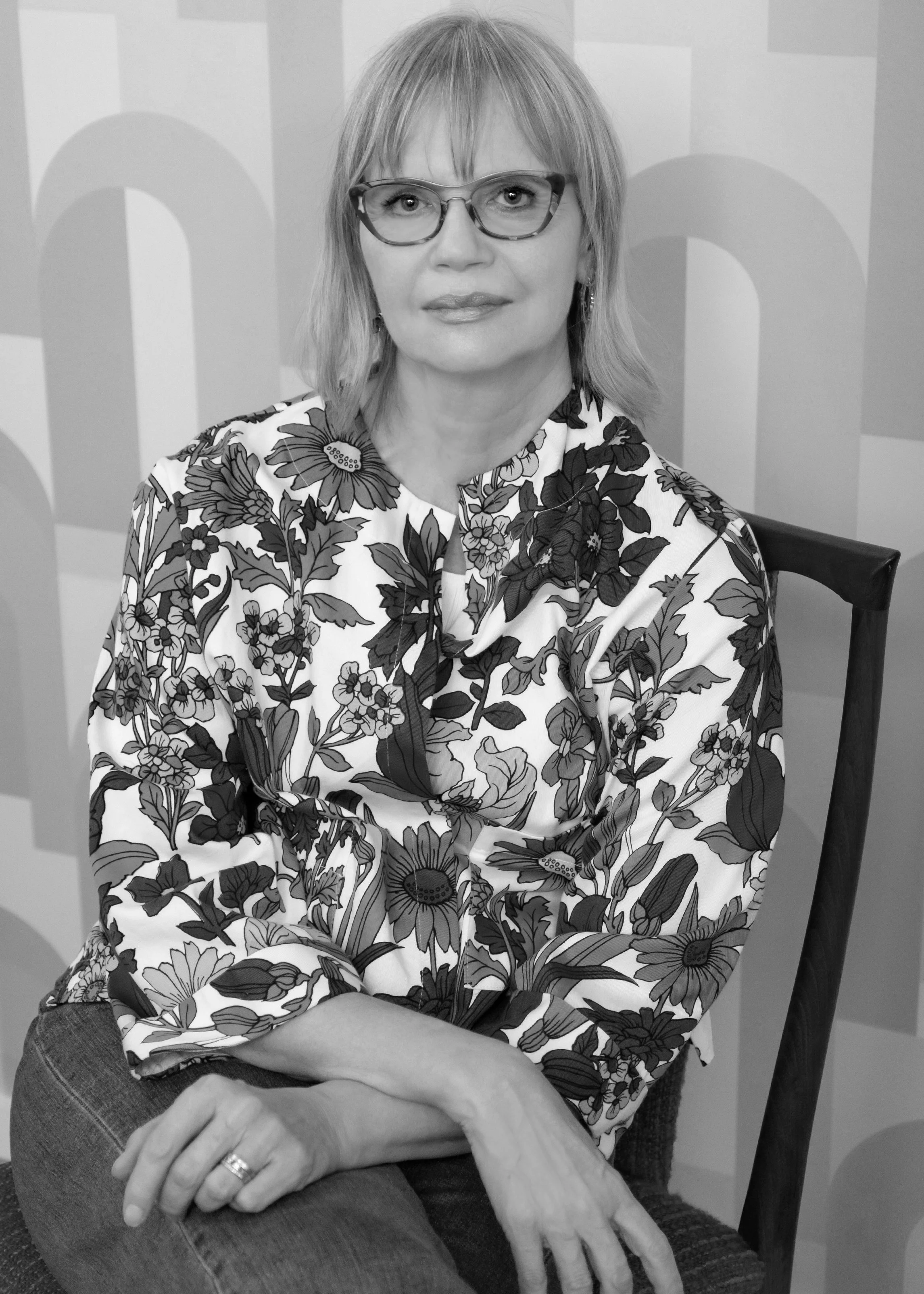 Woman sitting on a chair against a background of  geometric wallpaper BW