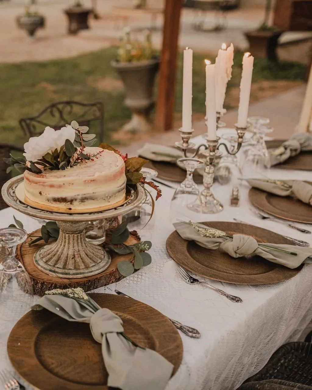 Wedding cake displayed on an elegant reception table with candles and floral details.